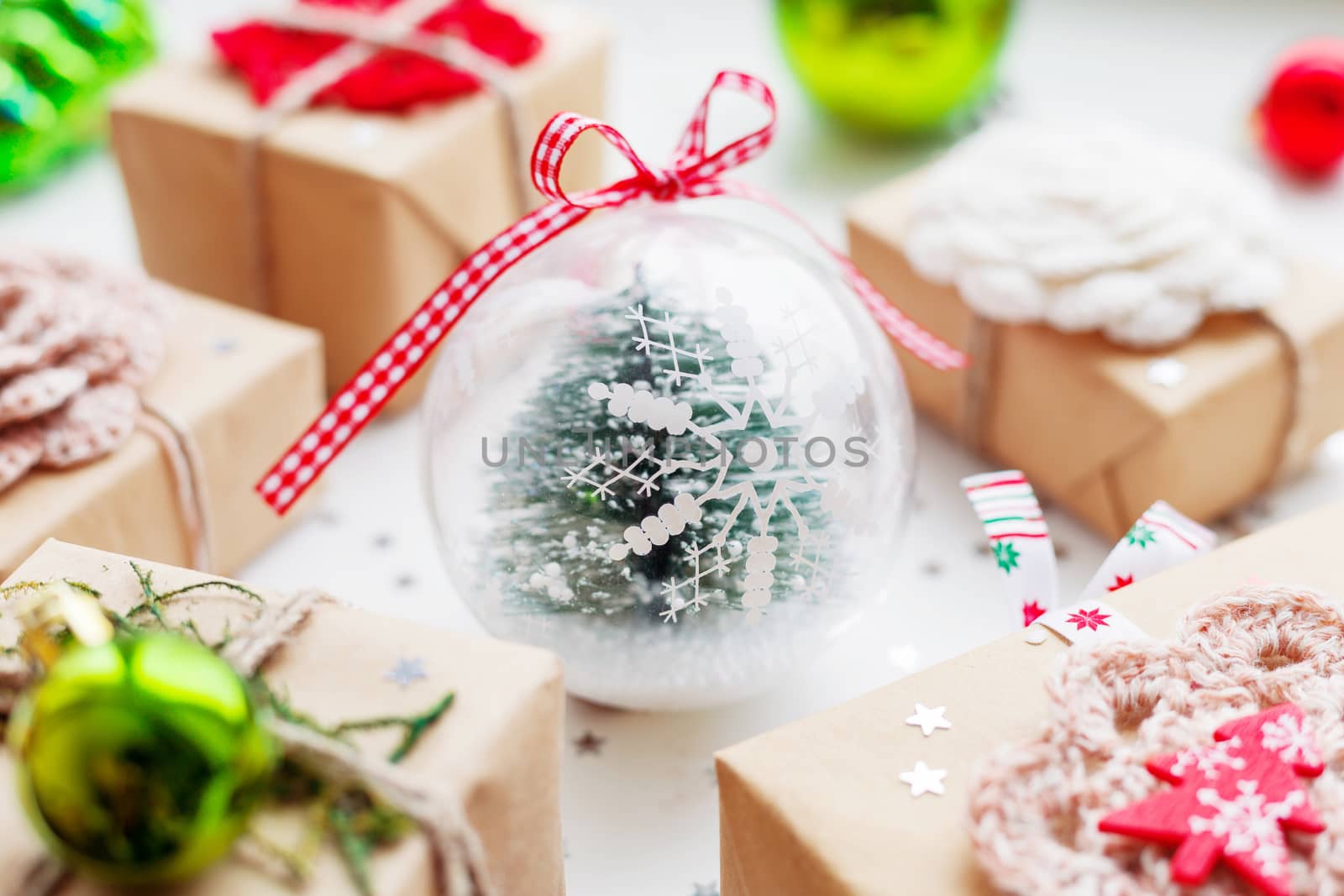 Christmas and New Year background with presents, decorations and transparent decorative ball with fir tree inside.