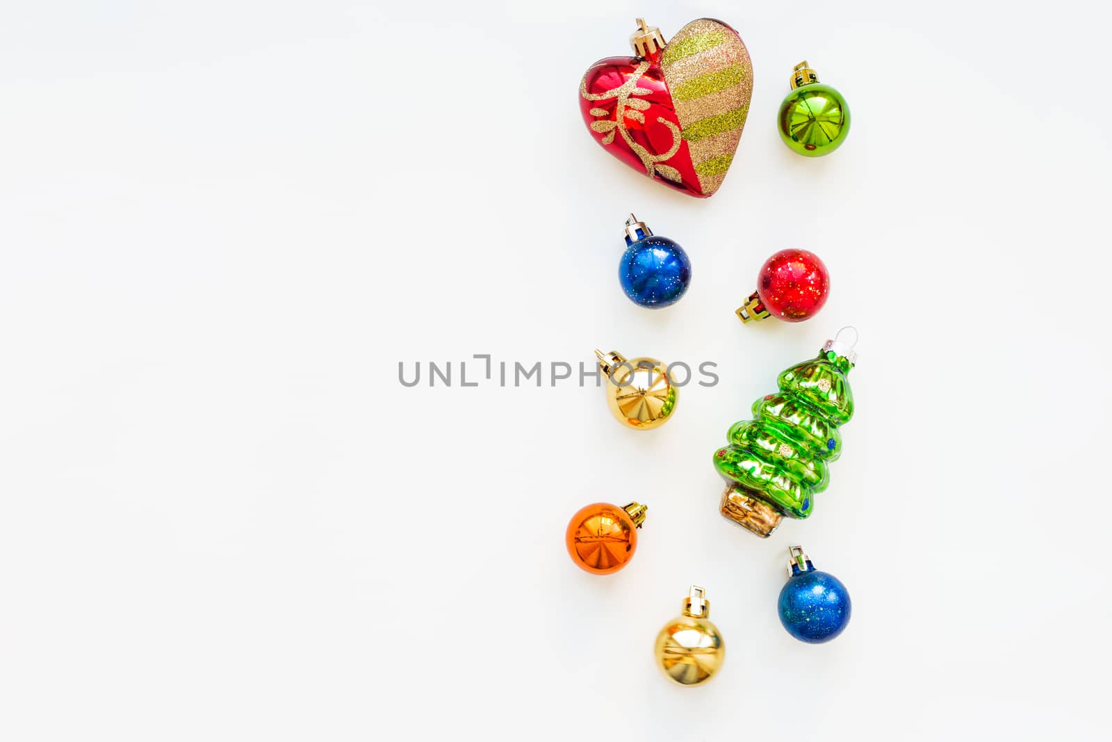 Christmas background with decorations. New Year symbol - fir tree. Shiny colorful balls and red heart. Flat lay, top view. Place for text.