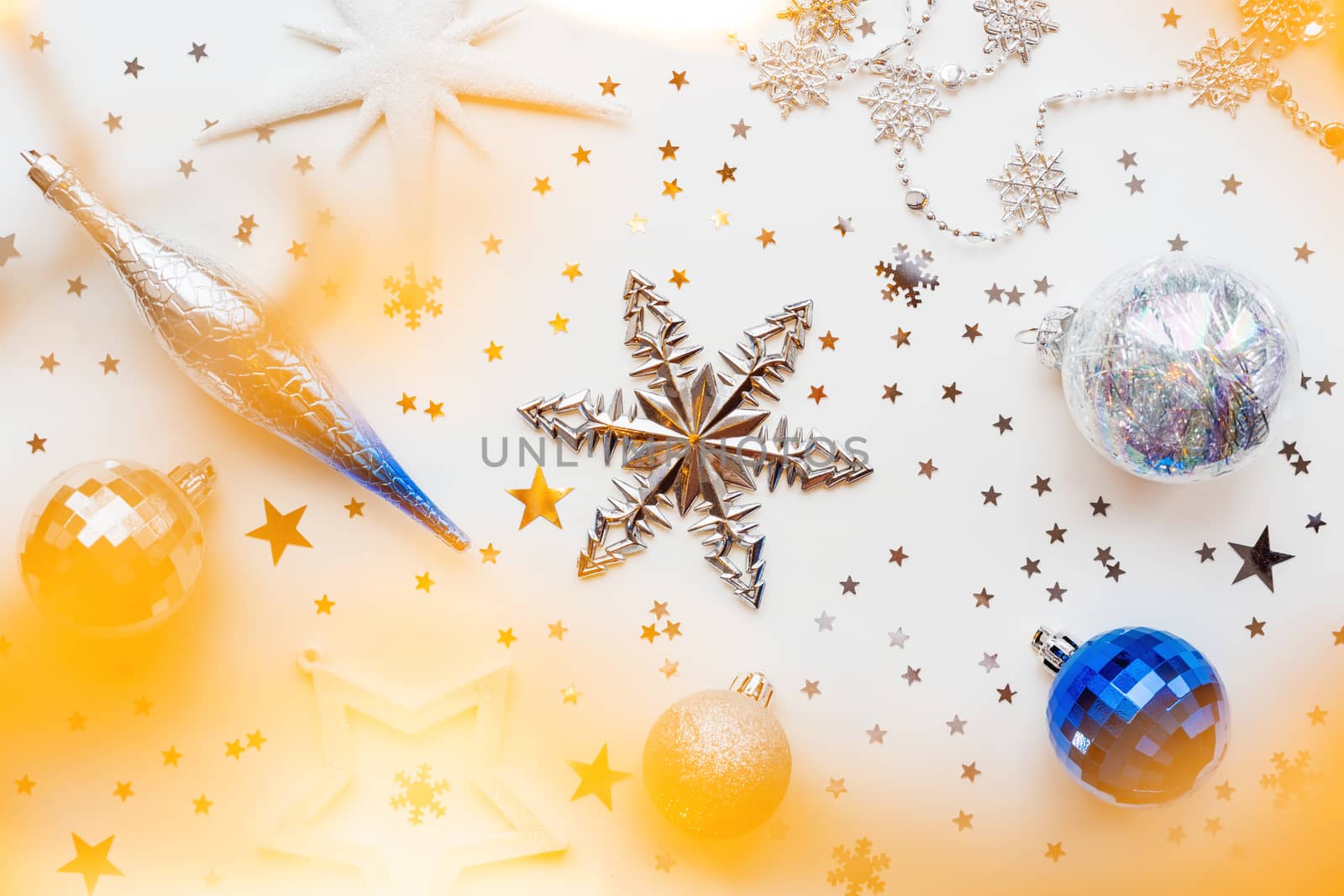 Christmas and New Year holiday background with decorations and light bulbs. Silver and blue shining balls, white snowflakes and star confetti. Flat lay, top view.