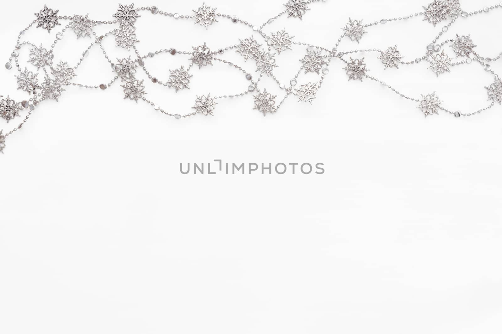 Clear white background with border of silver chain with snowflakes. Christmas and New Year holiday background with place for text. Flat lay, top view.