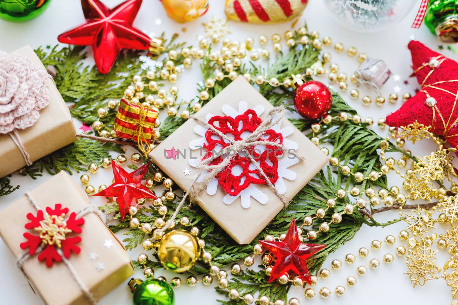 Christmas and New Year background with thuja branch, decorations and presents wrapped in craft paper with snowflakes.