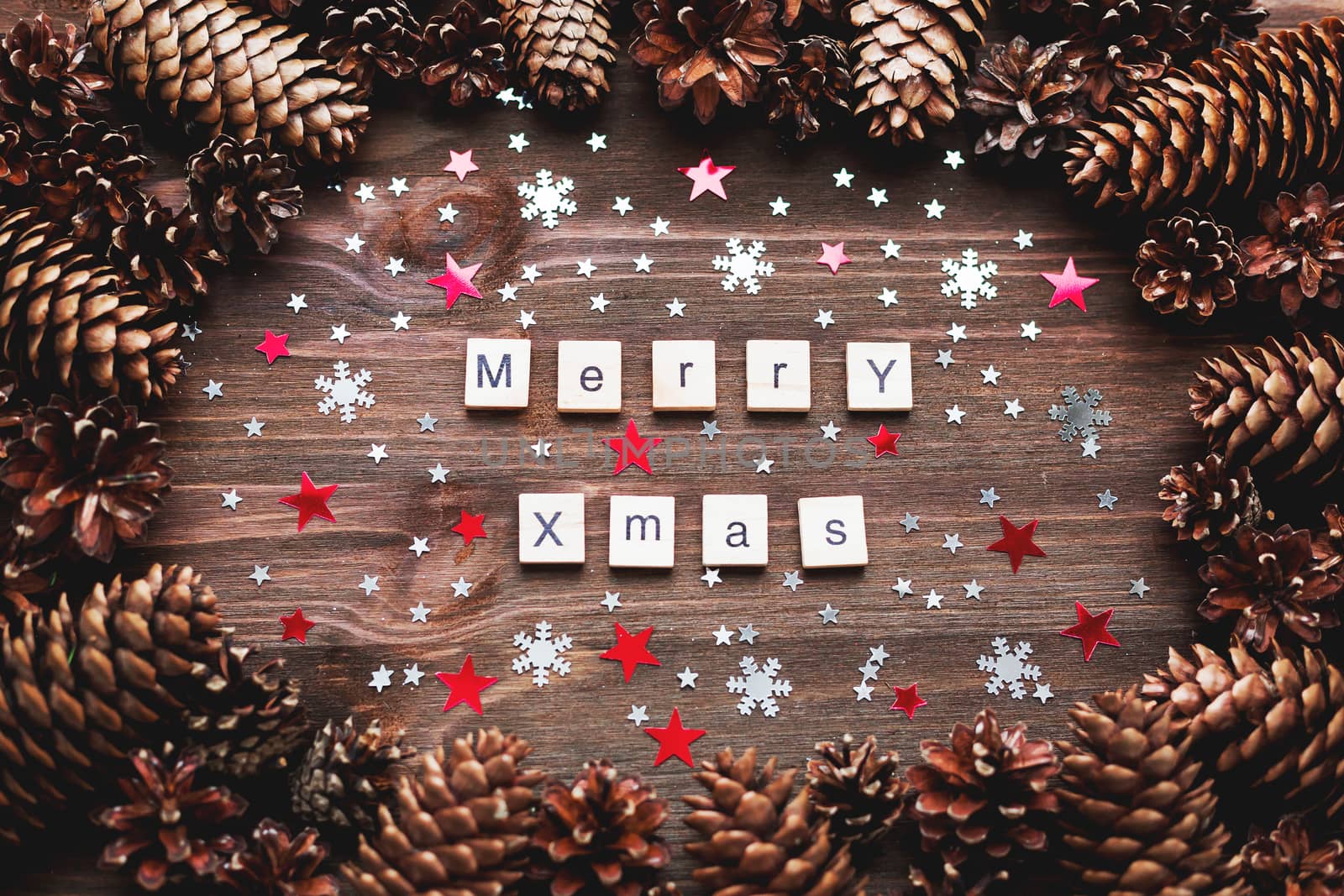 Rustic wooden background with pine cones. Merry Christmas background with bright snowflake confetti.