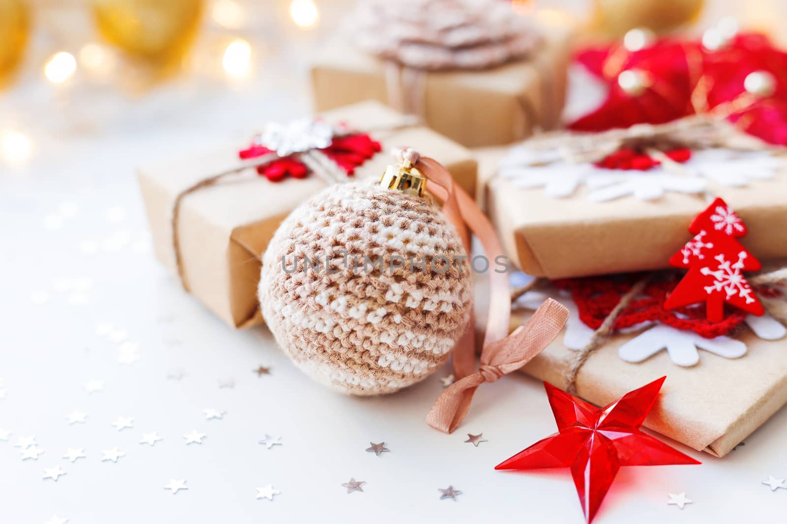 Christmas and New Year background with crocheted handmade ball, presents and decorations for Christmas tree. Holiday background with stars confetti and light bulbs. Place for text.