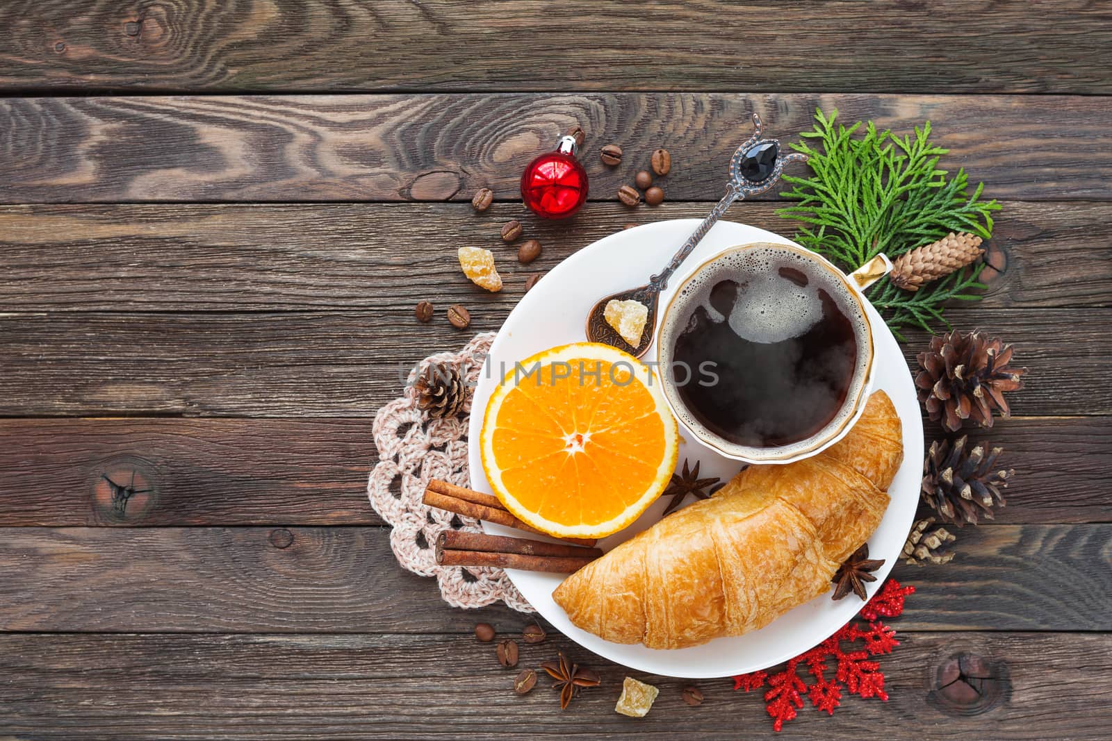Christmas and New Year 2017 background with continental breakfast - cup of hot coffee with cinnamon, fresh orange and croissant. Decorations - snowflake, crochet napkin, pine cones.