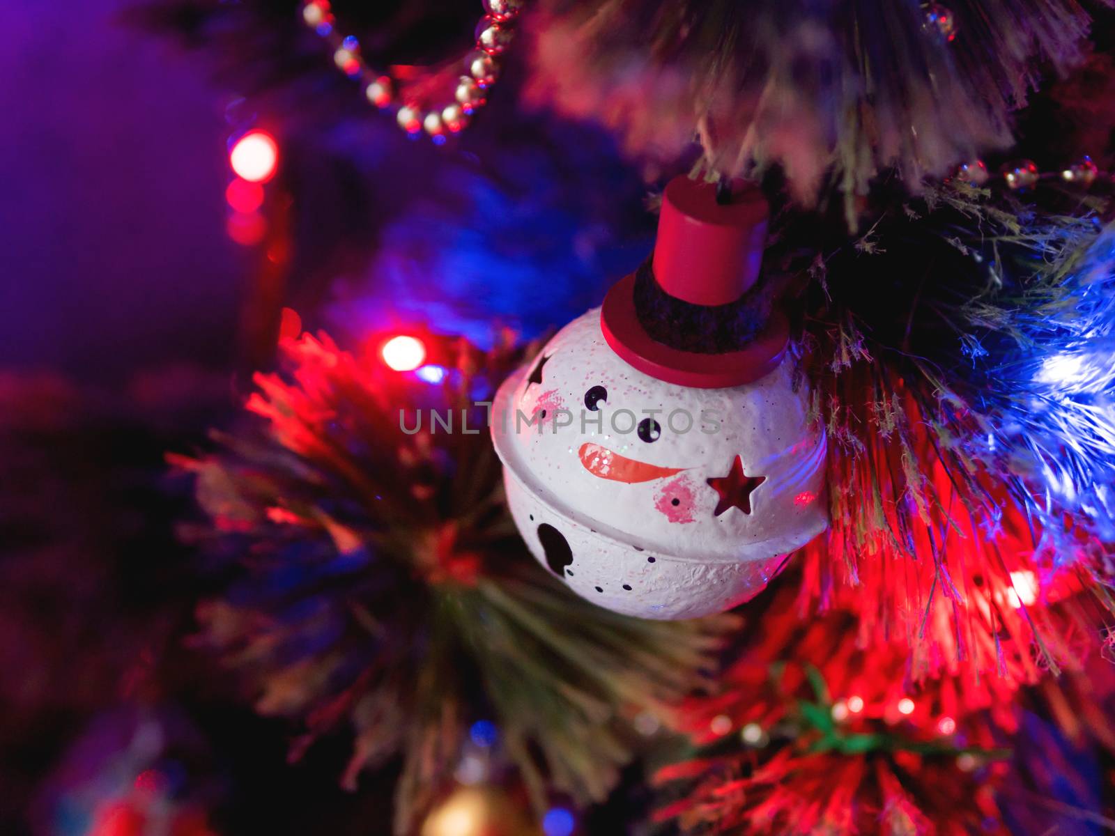 Funny snowman ball on Christmas tree. Colorful light bulbs and decorations on traditional fir tree for New Year celebration.