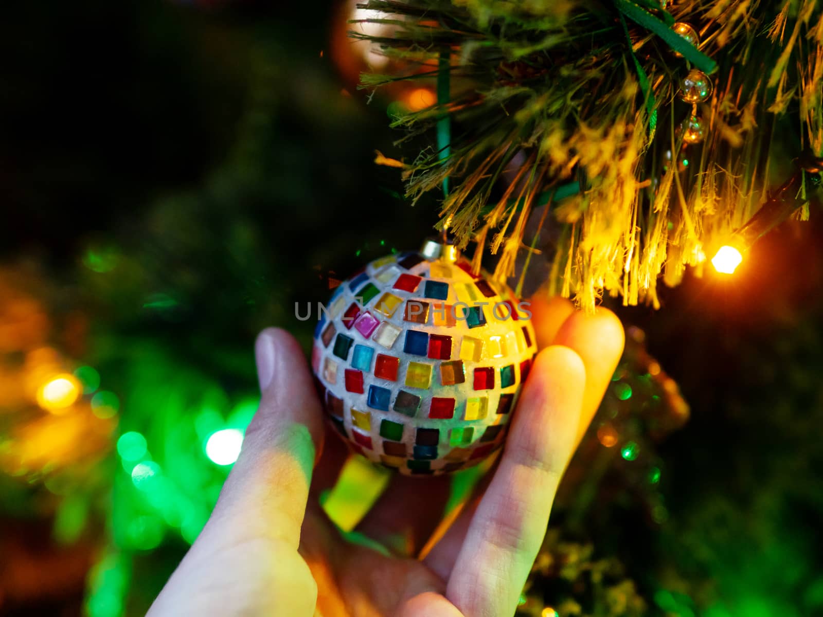 Hand made mosaic ball on Christmas tree. Colorful light bulbs and decorations on traditional fir tree for New Year celebration.