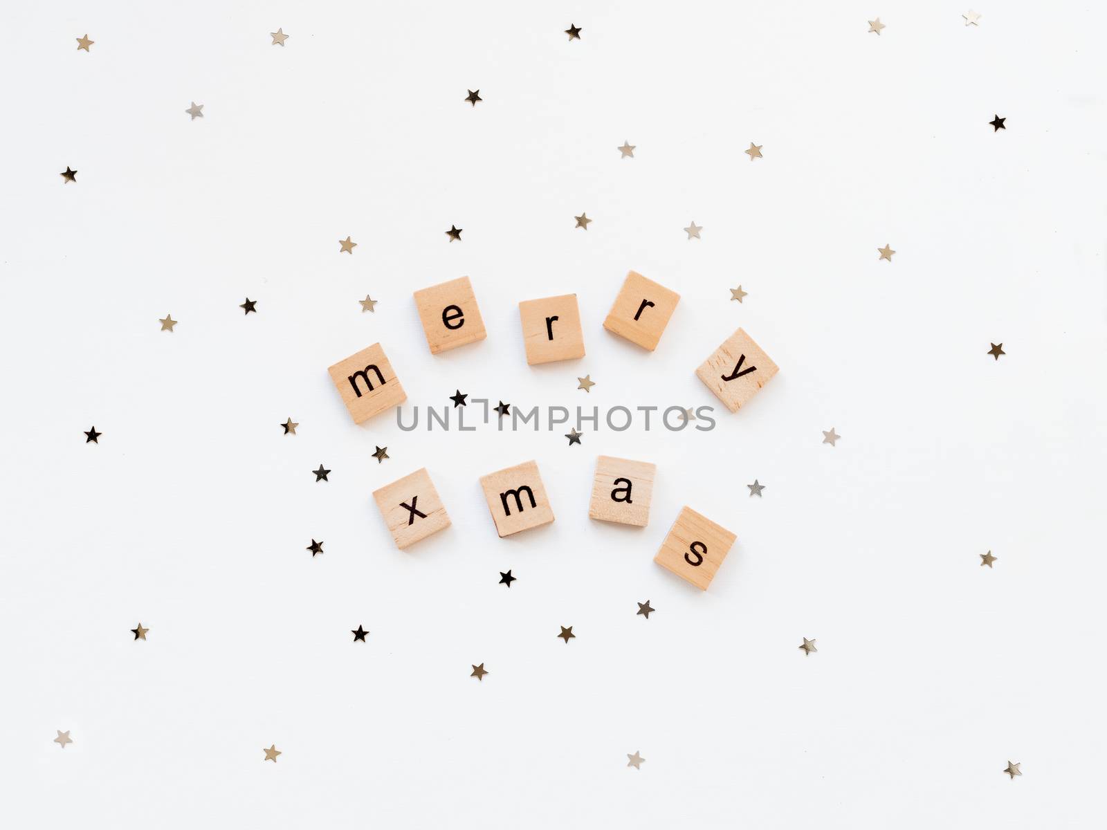 Christmas and New Year background with wooden words MERRY XMAS and star confetti. White copy space.