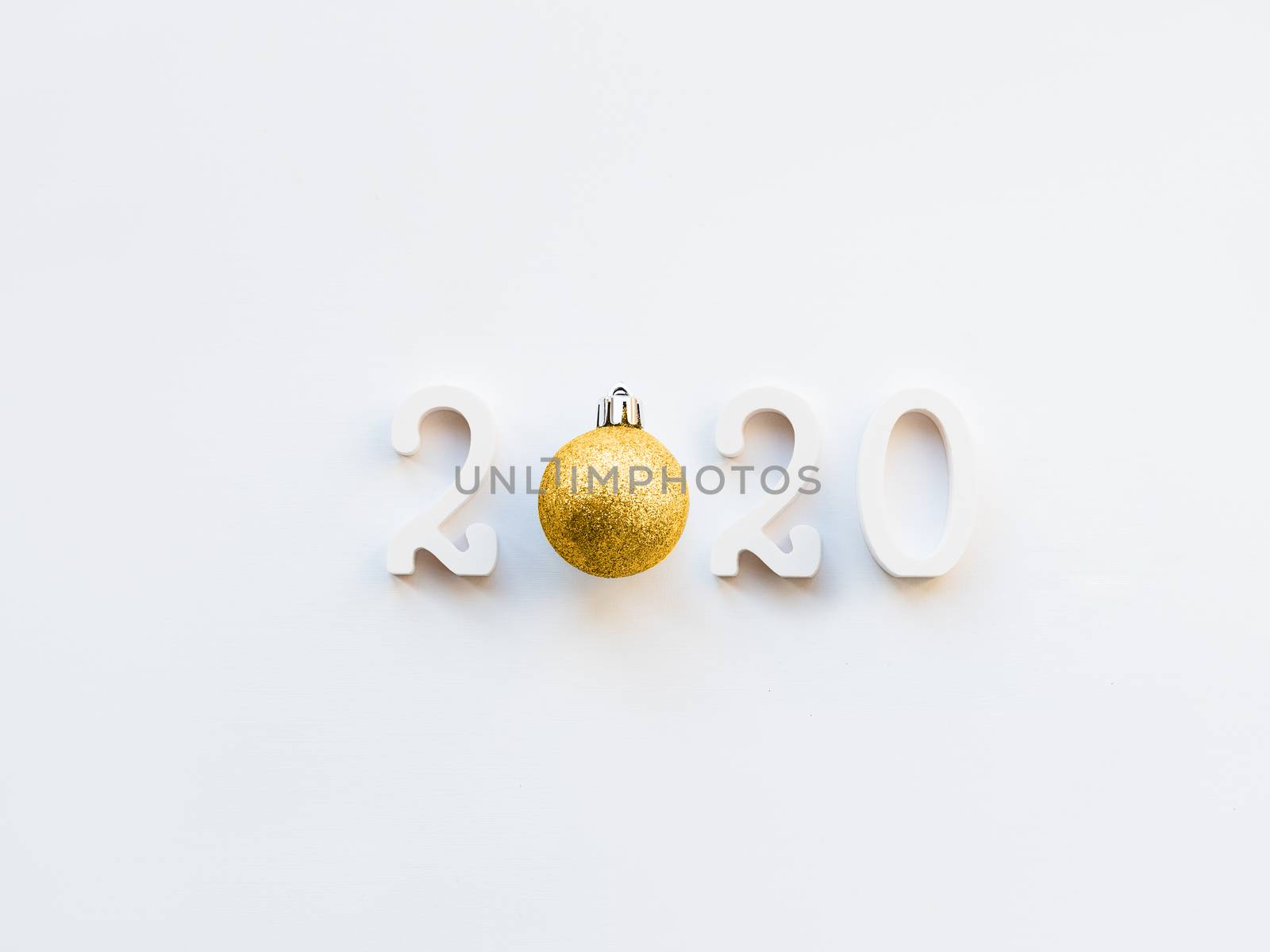 New Year 2020 background with golden ball. Numbers 2020 on white copy space with decorative ball for Christmas tree.