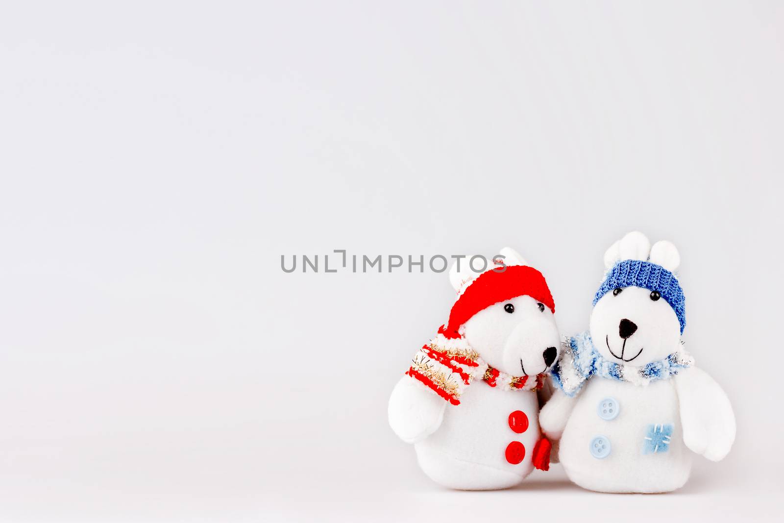 Pair of cute plush rabbits in warm clothes. Sweet couple of toys in scarfs and caps. Christmas background with empty space for text.