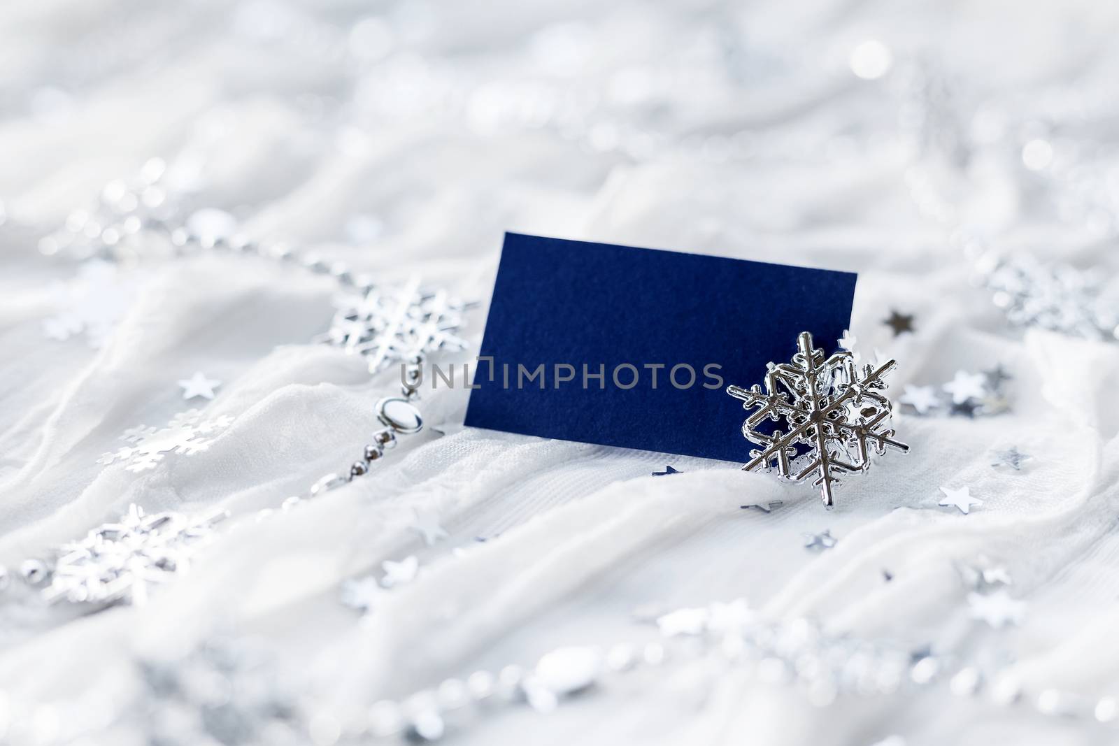 White holiday background with sparkling silver snowflakes, christmas decorations and empty piece of paper for your text.