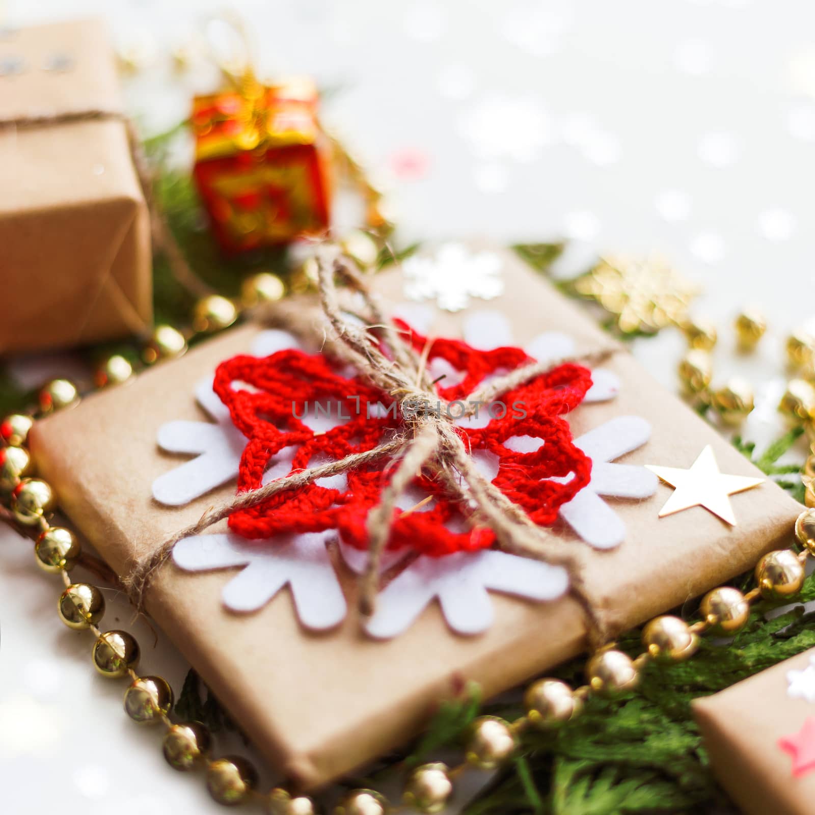 Christmas and New Year background with thuja branch, decorations and presents wrapped in craft paper with snowflakes.