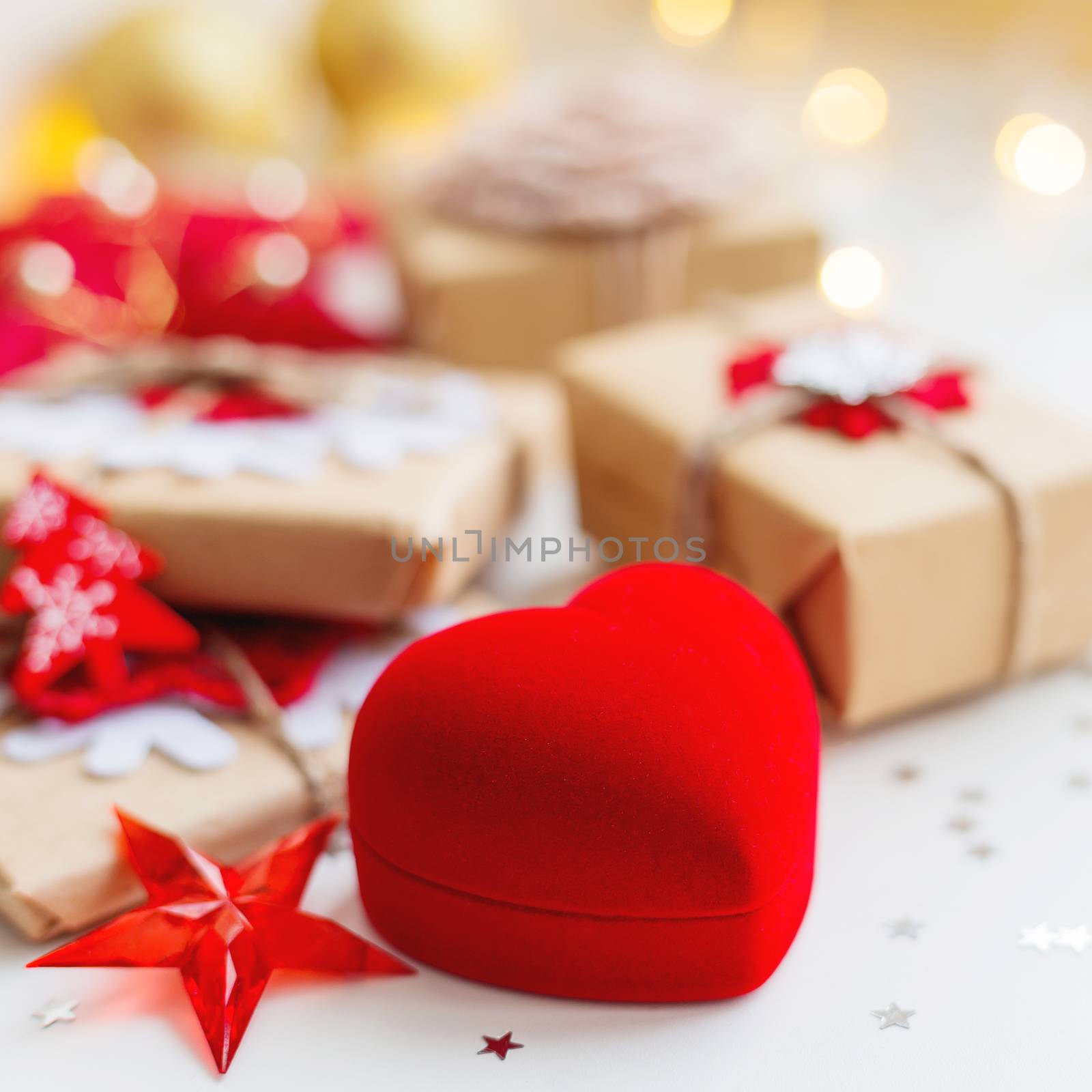 Christmas and New Year background with red box in shape of heart and presents, decorations for Christmas tree. Holiday background with stars confetti and light bulbs. Place for text.