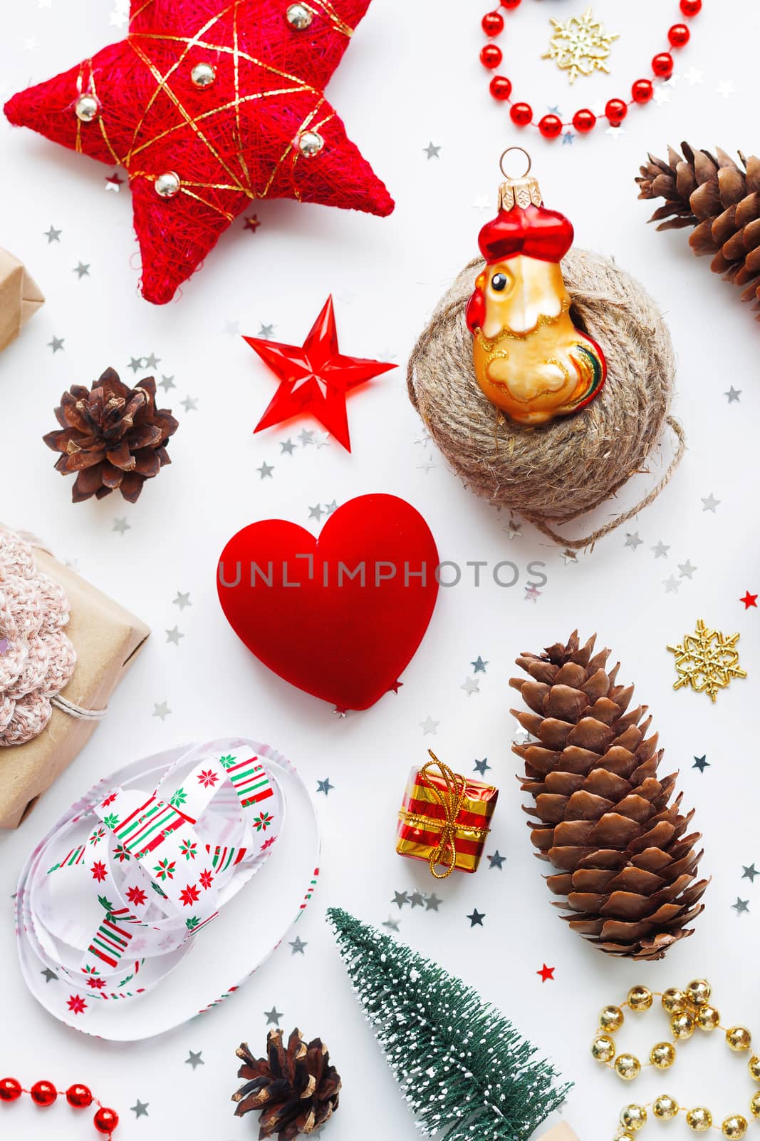 Christmas background with decorations. New Year 2017 symbol - Fire Rooster. Gifts in craft paper, pine cones, red hearts and confetti. Flay lay, top view.