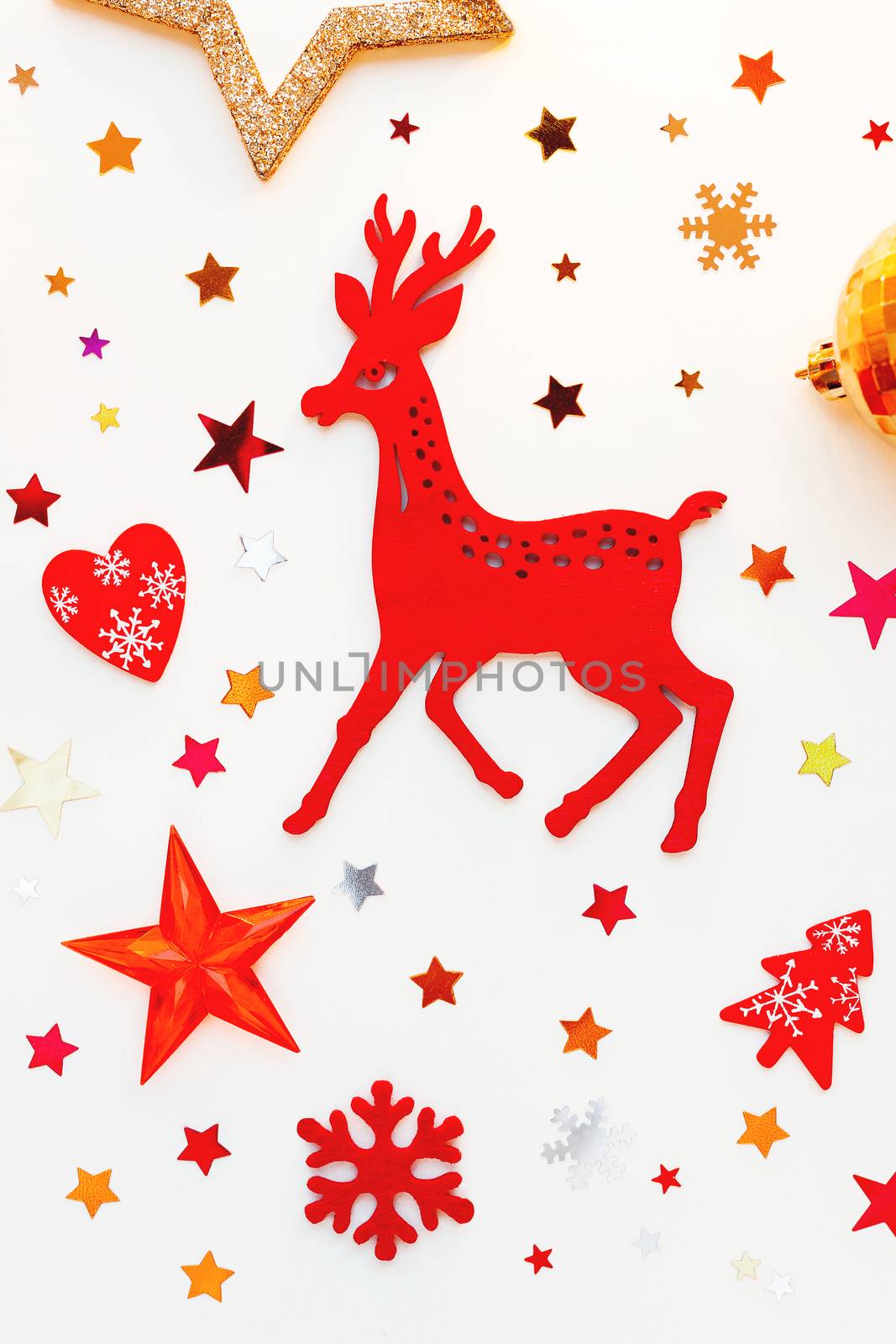 Christmas and New Year holiday background with decorations. Red deer and golden shining balls, snowflakes and star confetti. Flat lay, top view.