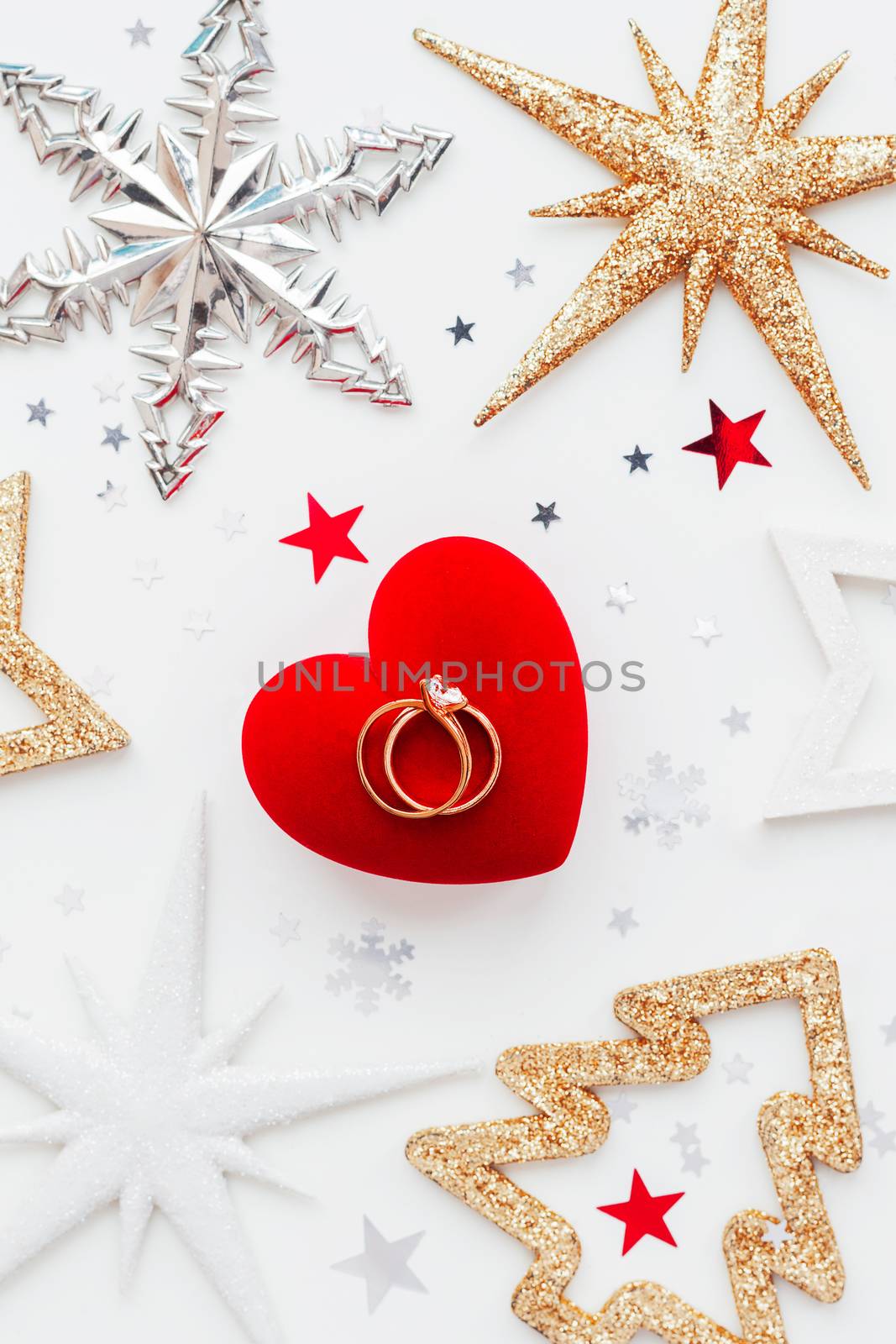 Christmas and New Year holiday background with decorations and wedding rings on gift heart box. Top view, flat lay.