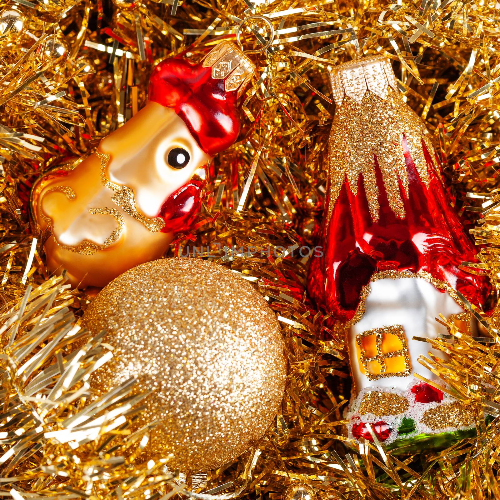 Golden glass rooster, toy house and ball in box with tinsel. Christmas and New Year decorations.