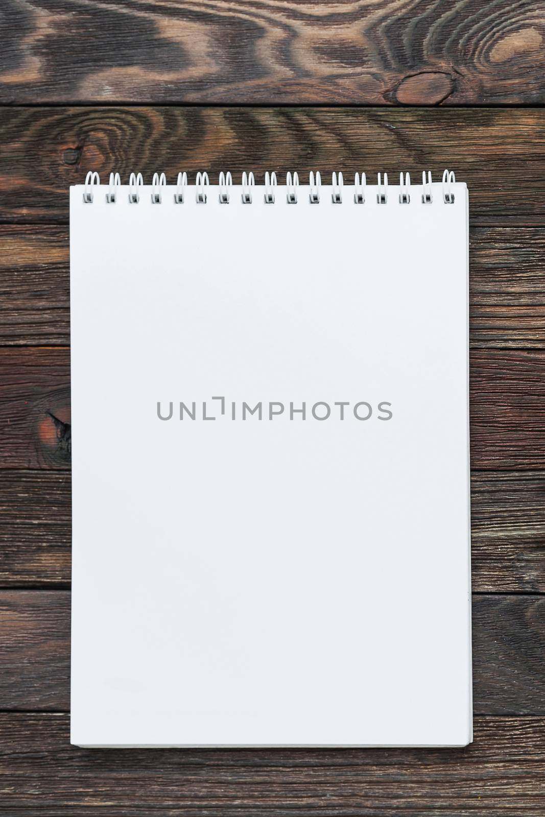 Wooden background with notepad. Clear white page may be used as mock up. Office supply for making notes or to do lists.