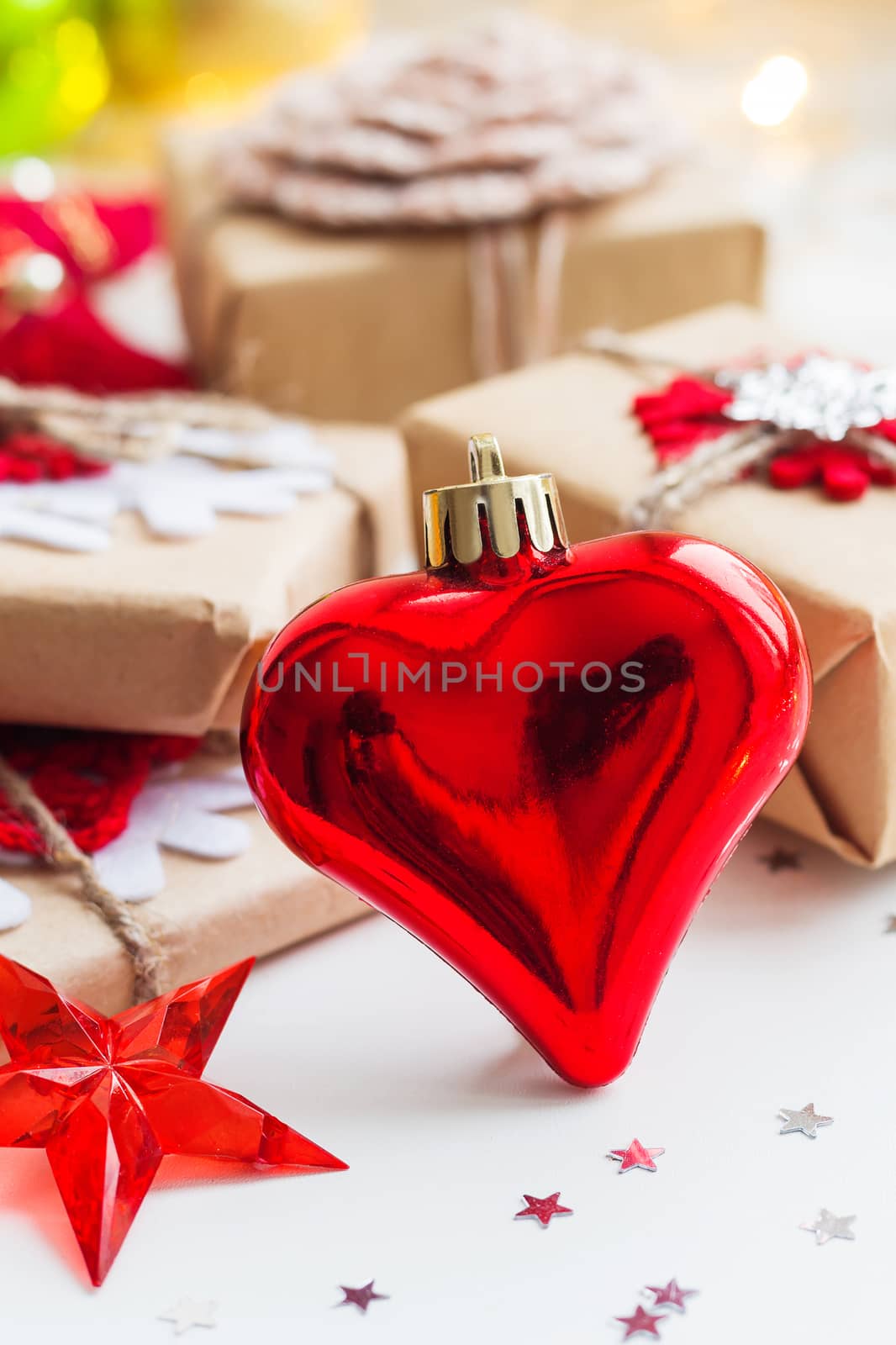 Christmas and New Year background with red decorative heart, presents and decorations for Christmas tree. Holiday background with stars confetti and light bulbs. Place for text.