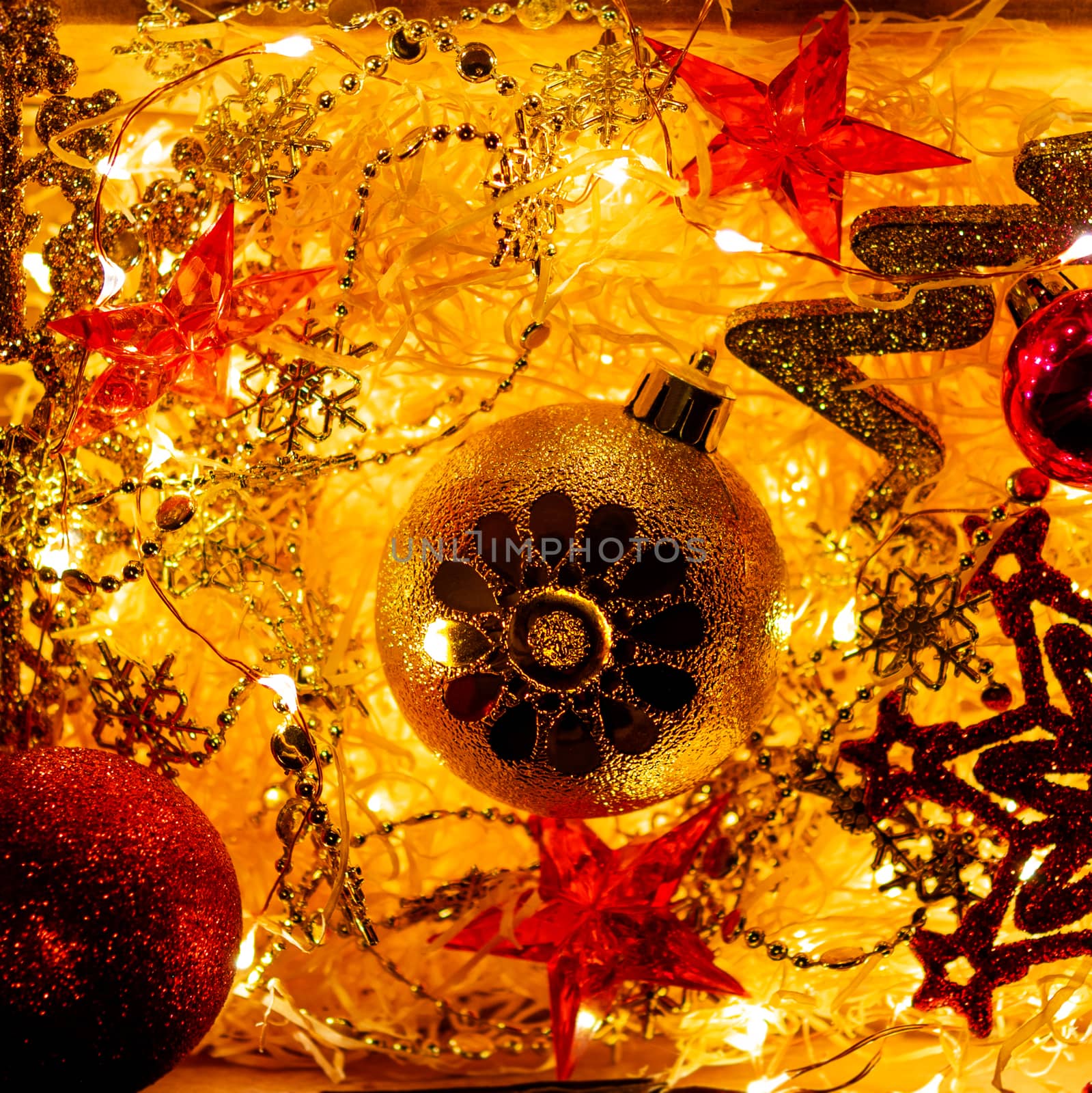 Cardboard box with Christmas and New Year decorations and light bulbs. Little baby touching red sparkling snowflake.