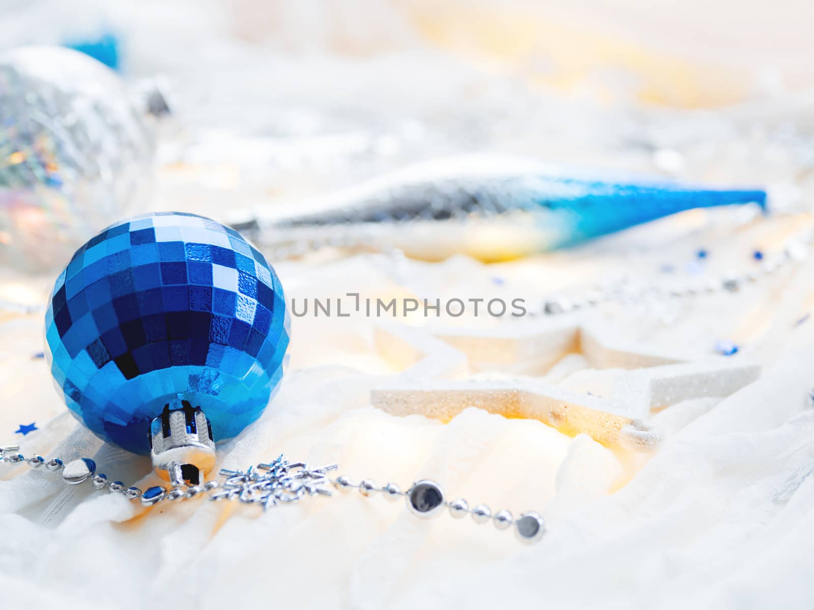 Christmas and New Year holiday background with decorations and light bulbs. Silver and blue shining balls, snowflakes and star confetti.