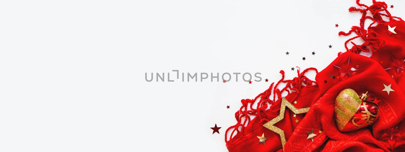 Christmas and New Year background. Bright red scarf with golden stars and confetti on white background. Folded warm accessory with copy space.