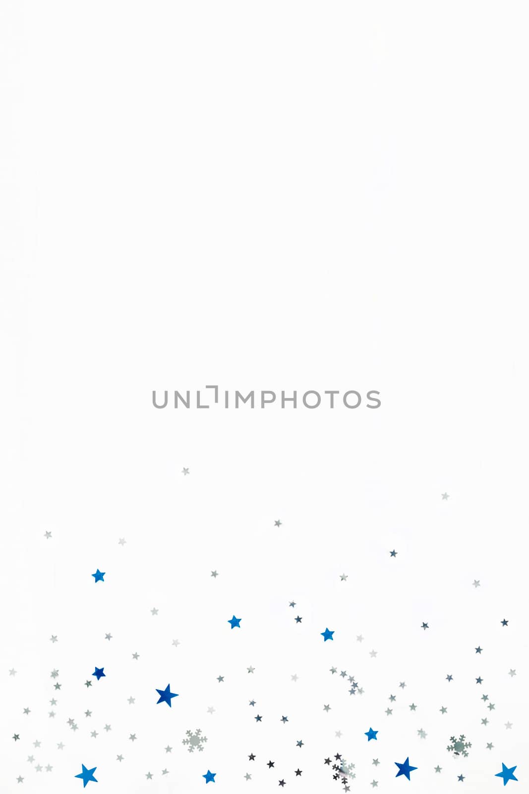 Christmas and New Year background with sparkling blue and silver stars confetti. Flat lay, top view. Place for text.