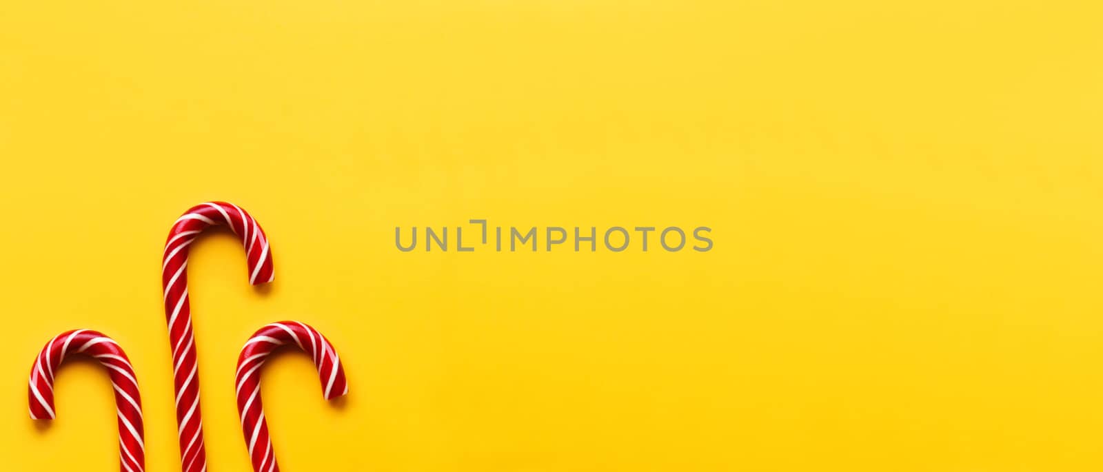 Three Christmas candy cones on yellow background. Colorful holid by aksenovko