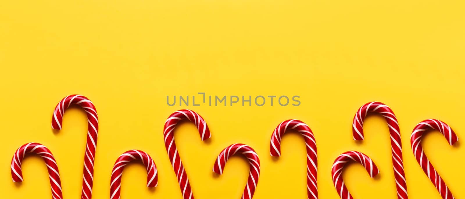Banner with Christmas candy cones on yellow background. Colorful by aksenovko