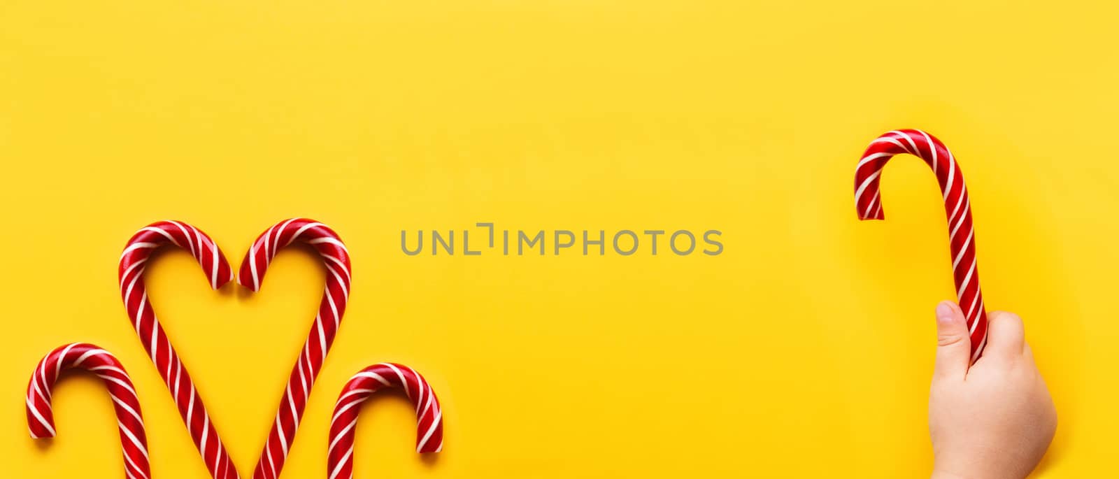 Three Christmas candy cones on yellow background. Colorful holid by aksenovko