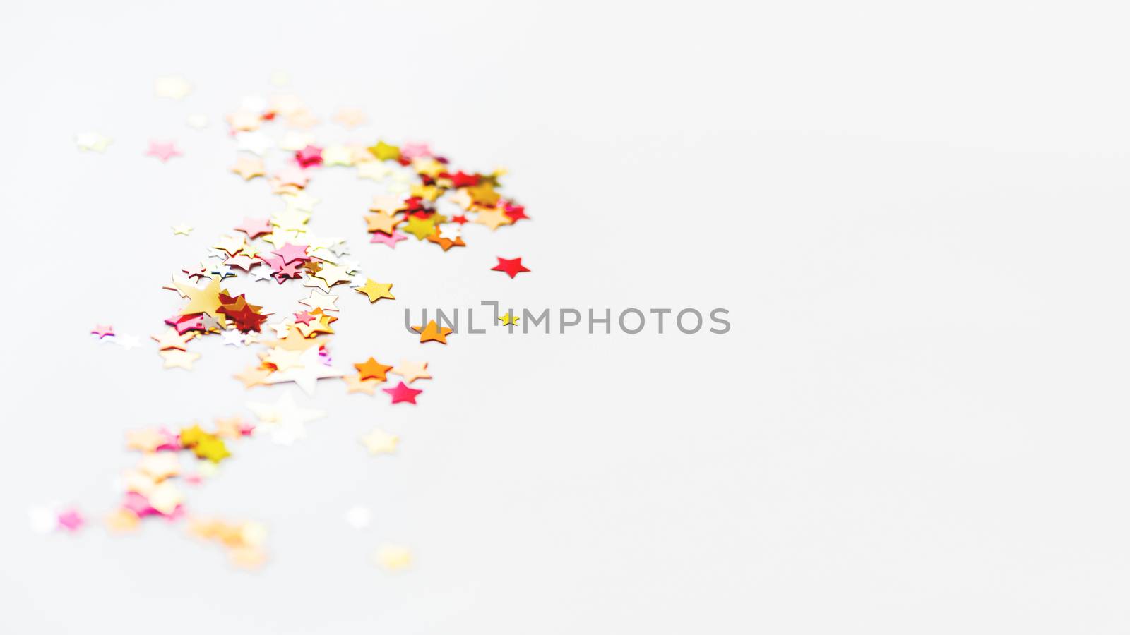 White holiday background with colorful star confetti. Good background for Christmas and New Year cards.