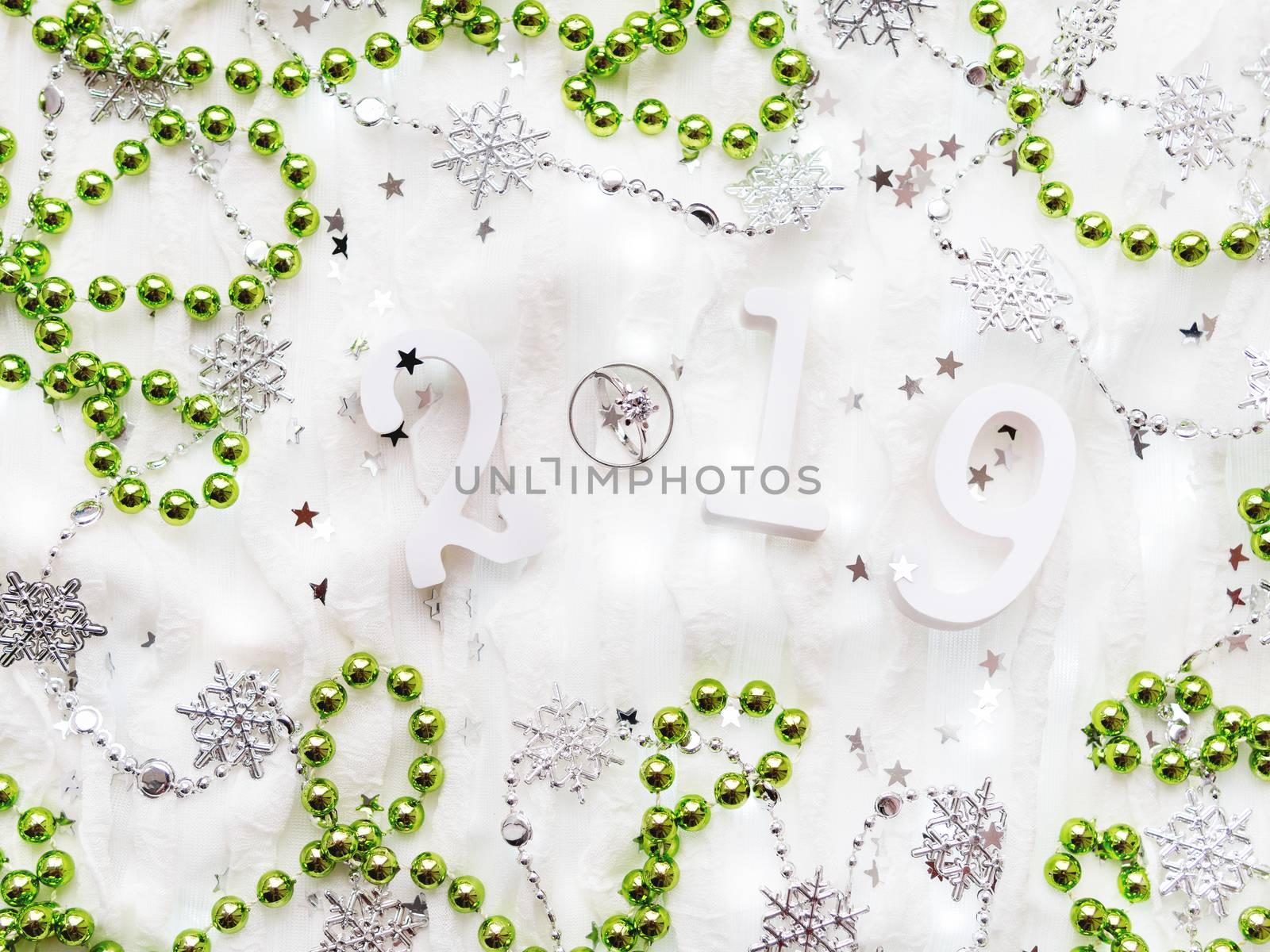 Christmas and New Year background with numbers 2019, green decorations, wedding rings and light bulbs.