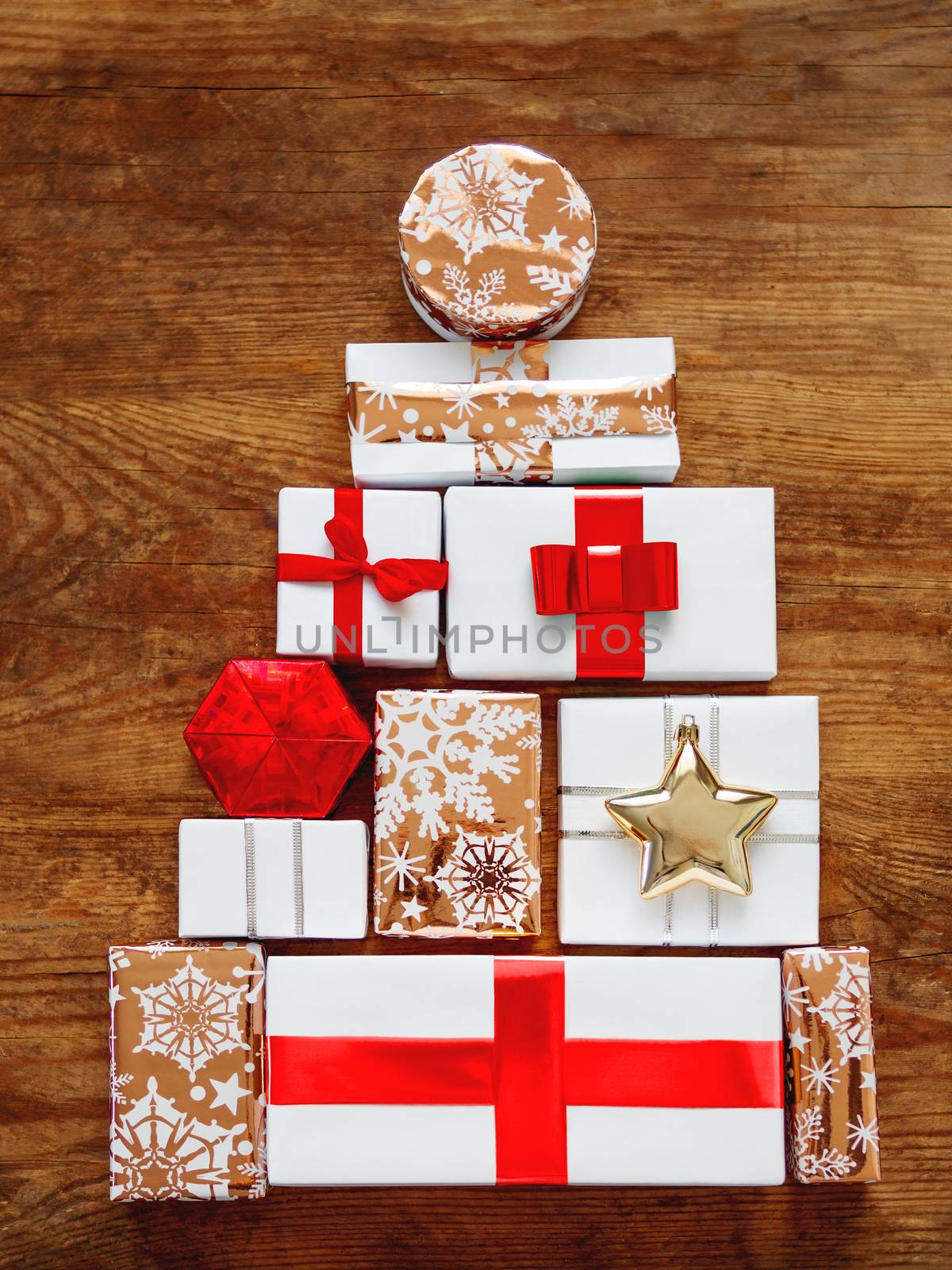 New Year presents in shape of Christmas tree on shabby wooden background. Gifts in white and golden paper with bright ribbons.