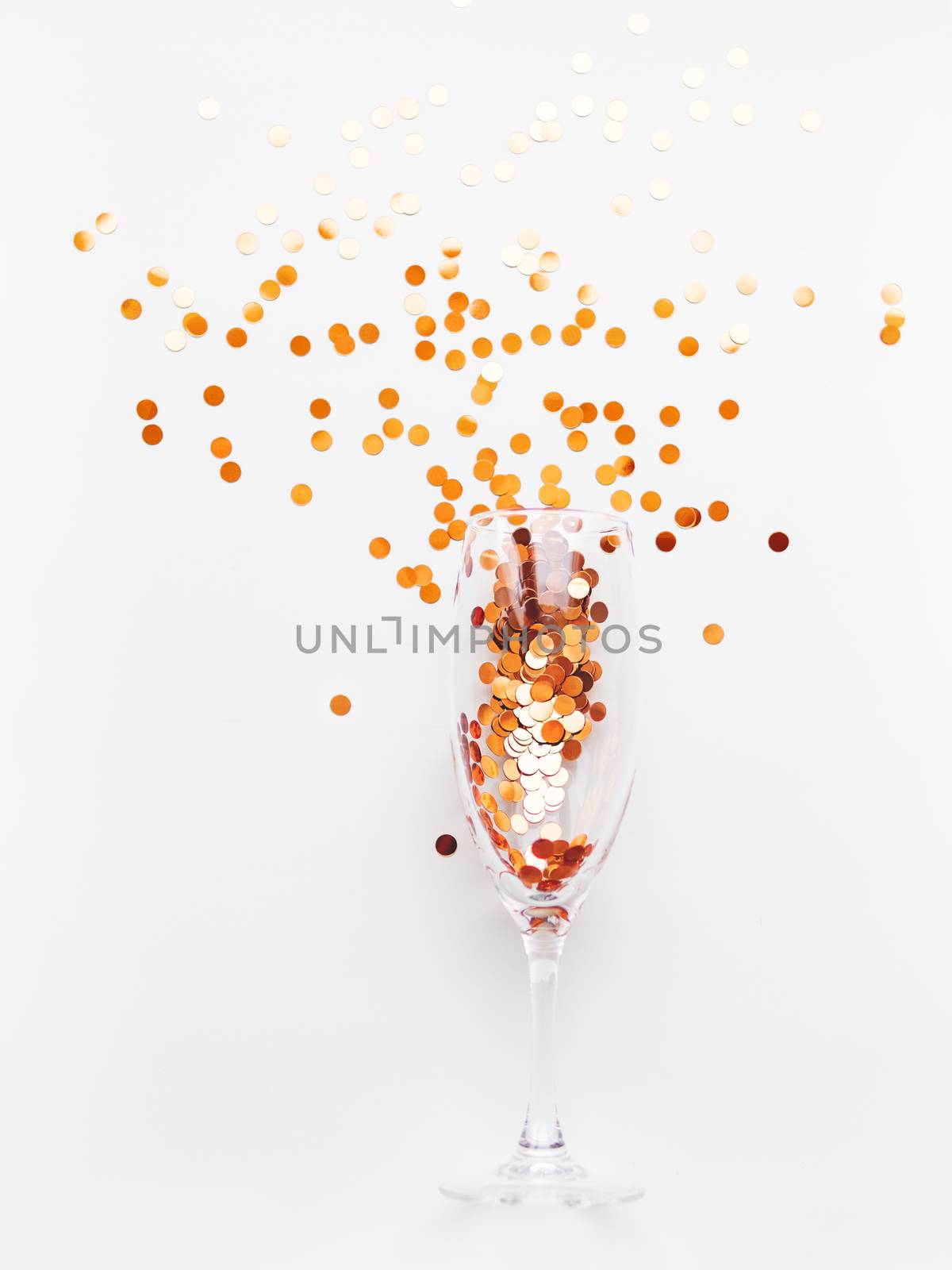 Transparent wine glass with golden spangles. Festive copy space with crockery on white background.
