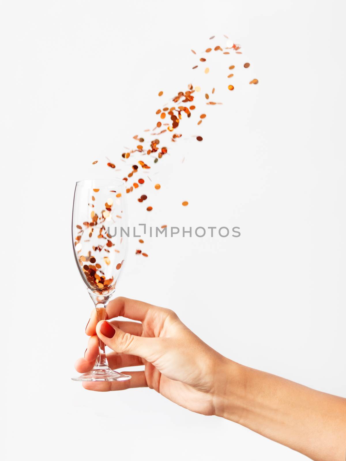 Woman holding transparent wine glass with golden spangles. Festive copy space with crockery on white background.
