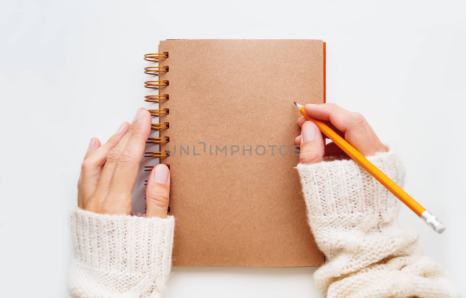 Woman is preparing to write or draw something in notepad with craft paper pages.