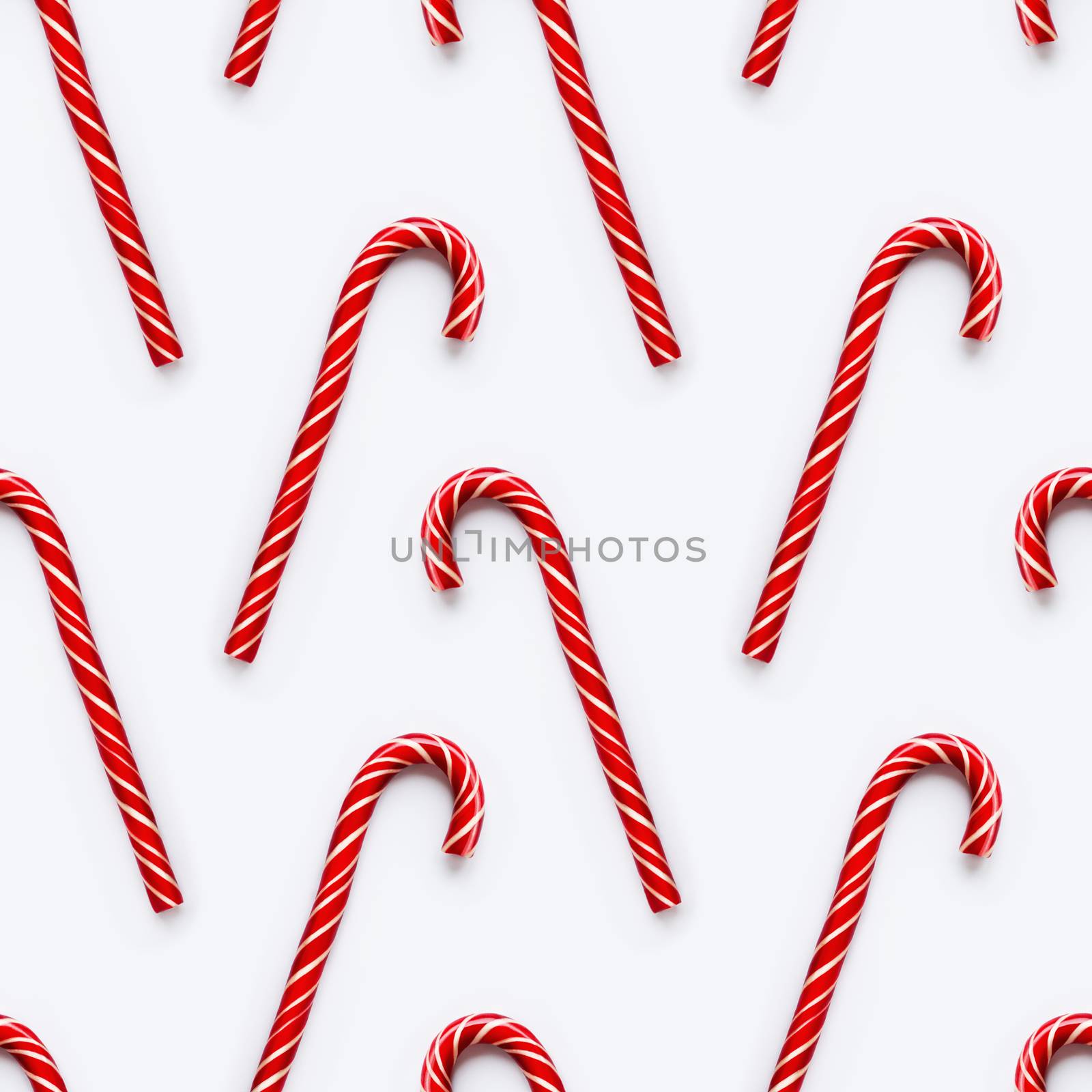Seamless pattern of Christmas candy cone on white background. Colorful holiday sweet lollipop. Dessert wtih red and white stripes.