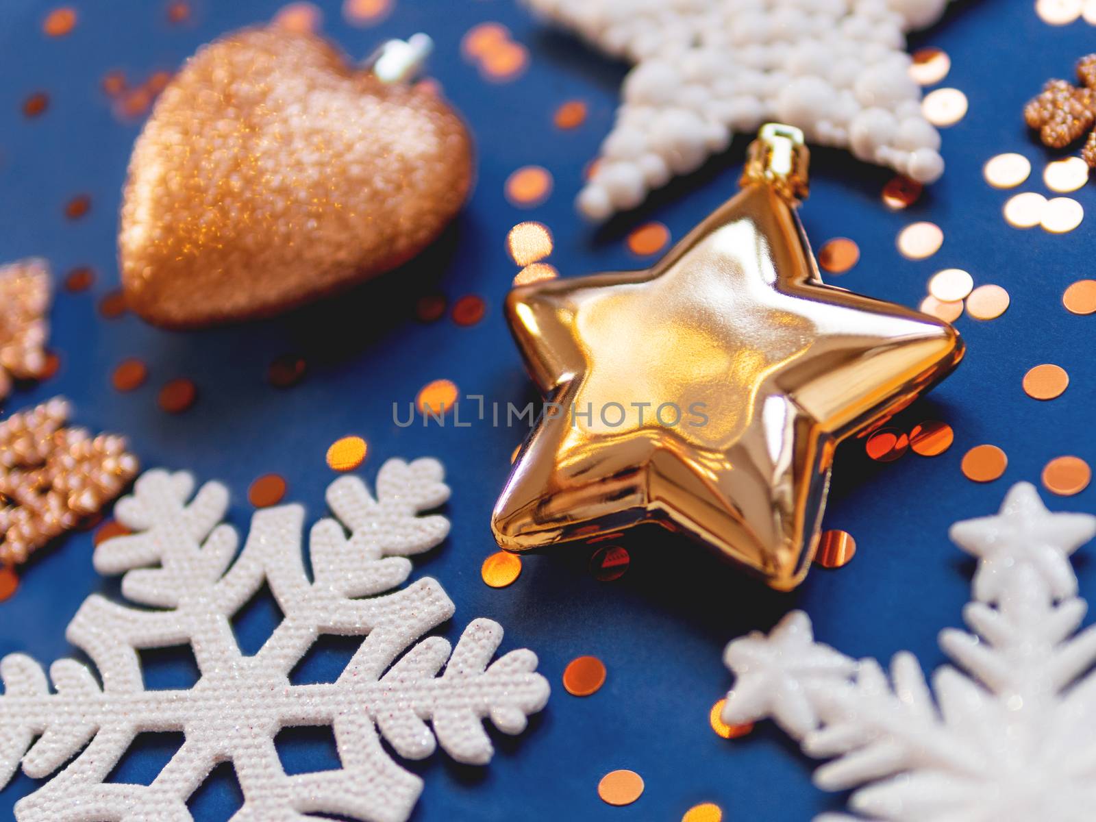 Golden and white decorations for Christmas tree. New Year decorative stars and snowflakes on classic blue background.