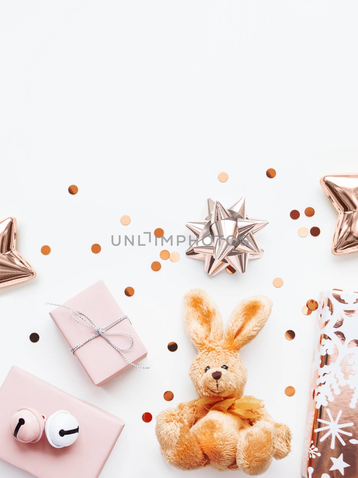 Holiday presents in shadows of pink - fluffy toy rabbit, gifts with decorative bells, sparkling confetti, golden star. Presents for little girl.