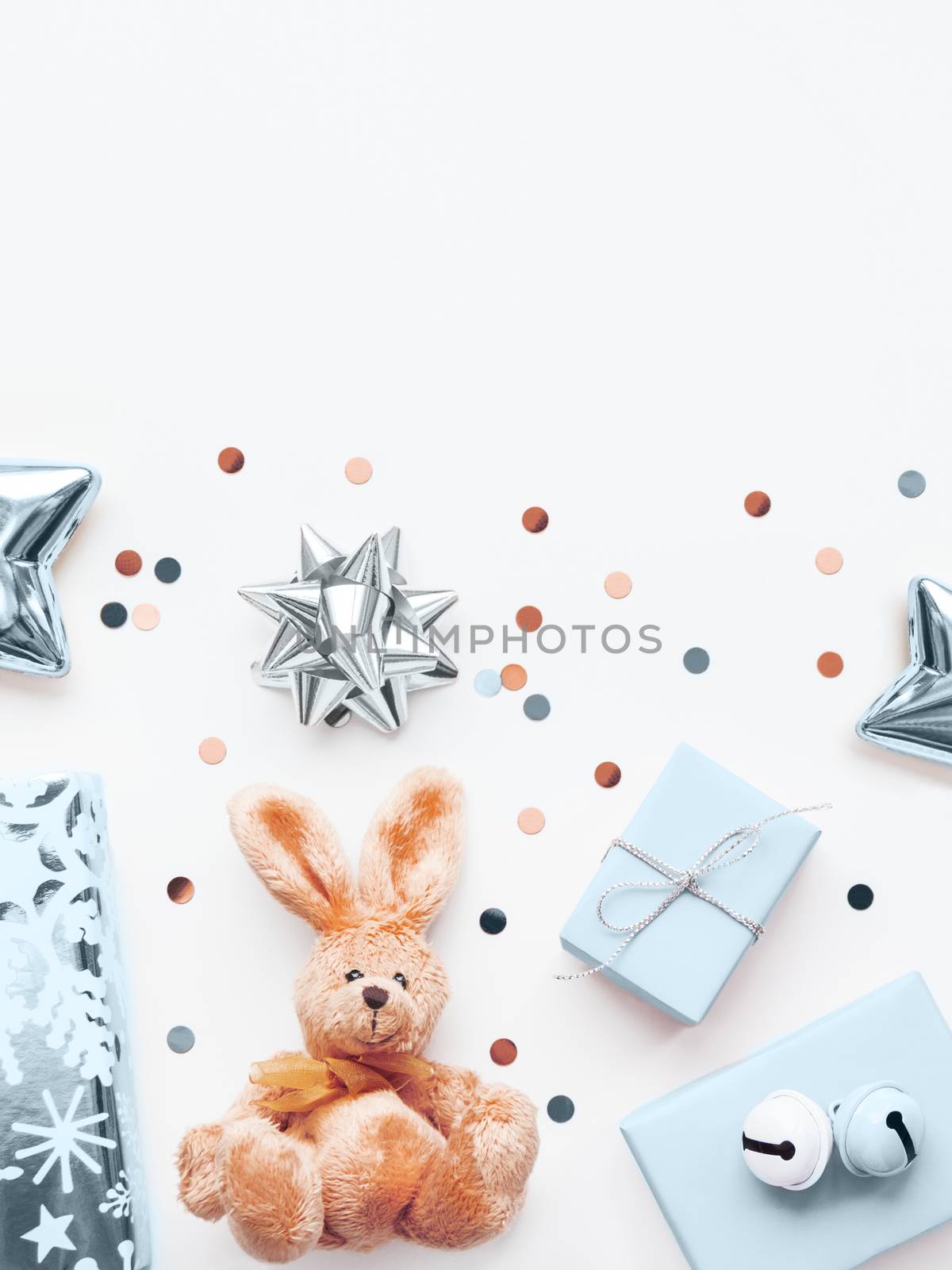 Holiday presents in shadows of blue and silver - fluffy toy rabbit, gifts with decorative bells, sparkling confetti, stars. Presents for little boy.