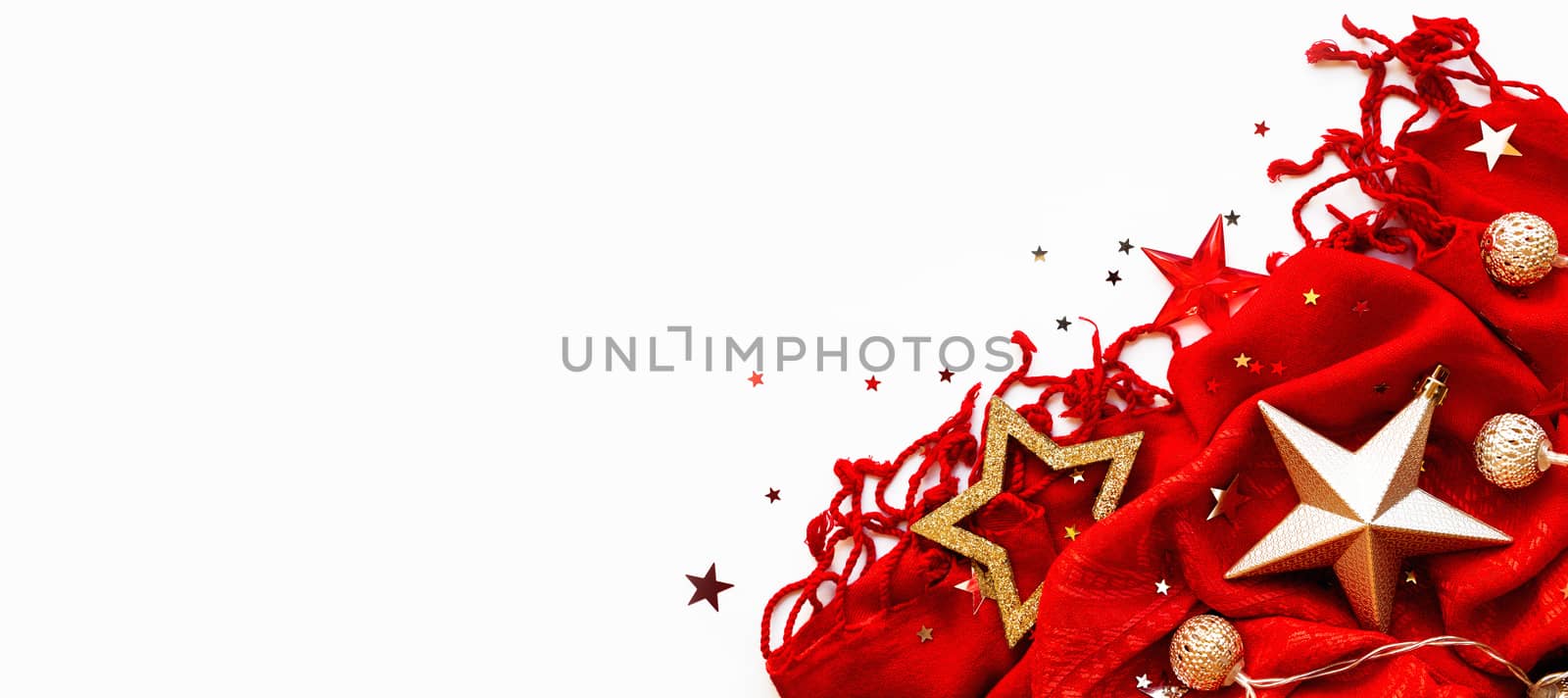 Christmas and New Year background. Bright red scarf with golden stars and confetti on white background. Folded warm accessory with copy space. by aksenovko