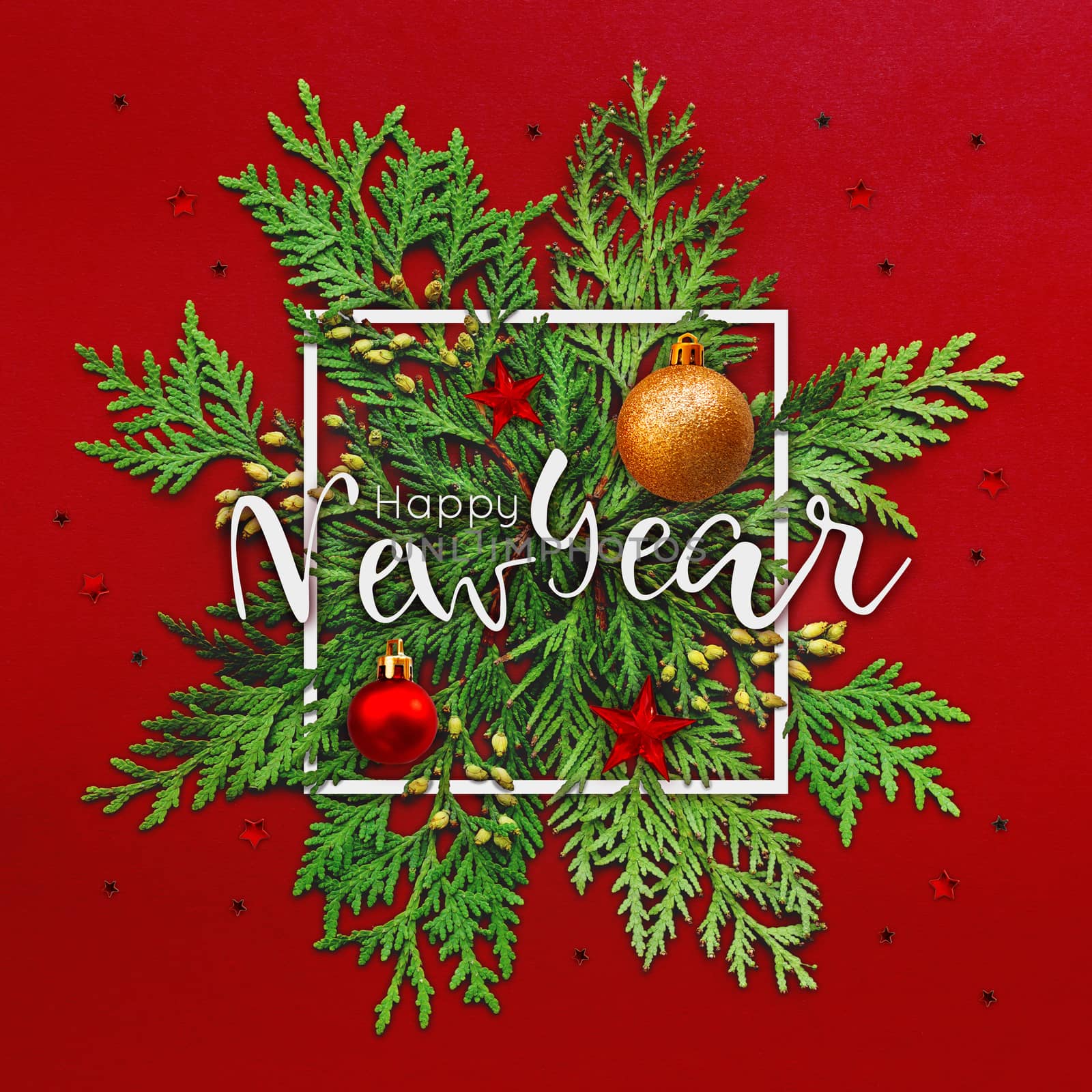 Christmas background with thuja branches and words HAPPY NEW YEAR in white square frame. Trendy Xmas greeting with stars and ball decorations on red backdrop.