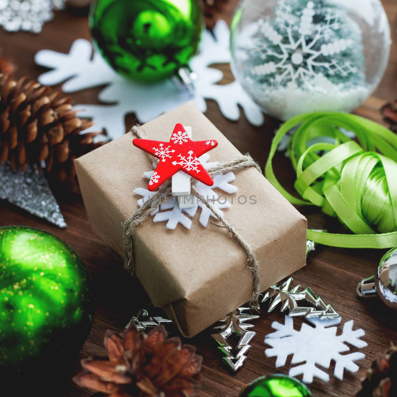 Christmas and New Year background with presents, ribbons, balls and different green decorations on wooden background. Gift packed in craft paper with red star.