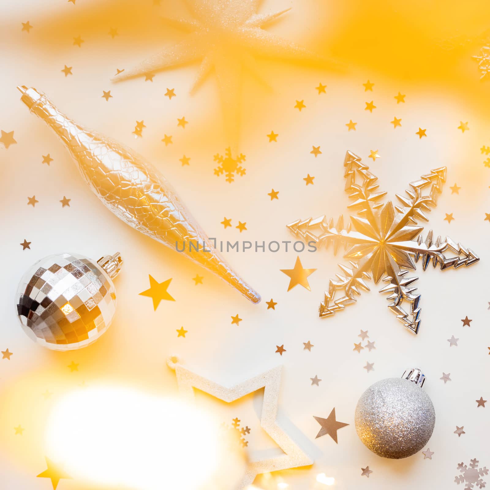 Christmas and New Year holiday background with decorations and light bulbs. Silver and blue shining balls, white snowflakes and star confetti. Flat lay, top view.