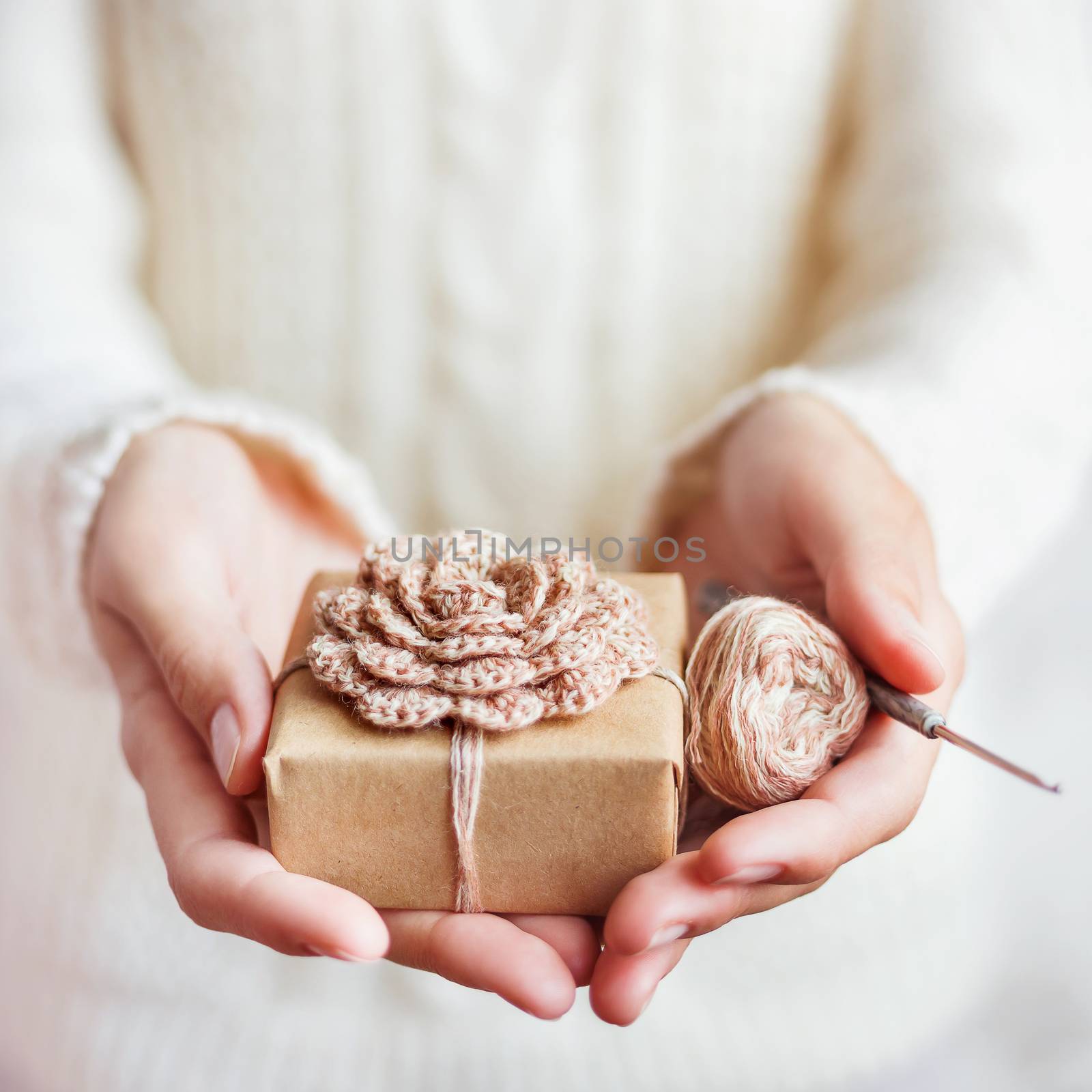 Woman in white knitted sweater holding a present wrapped in craf by aksenovko