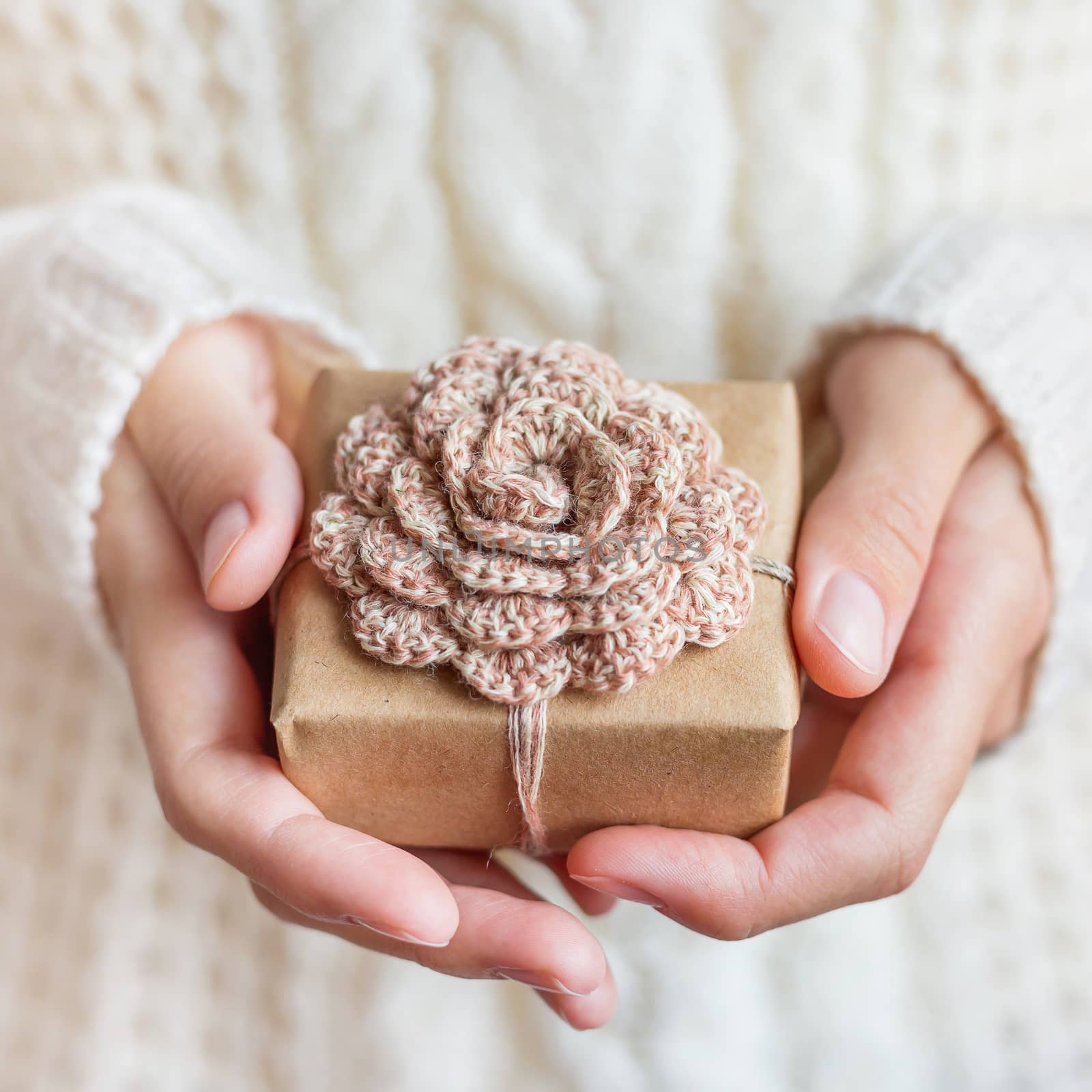 Woman in white knitted sweater holding a present wrapped in craf by aksenovko