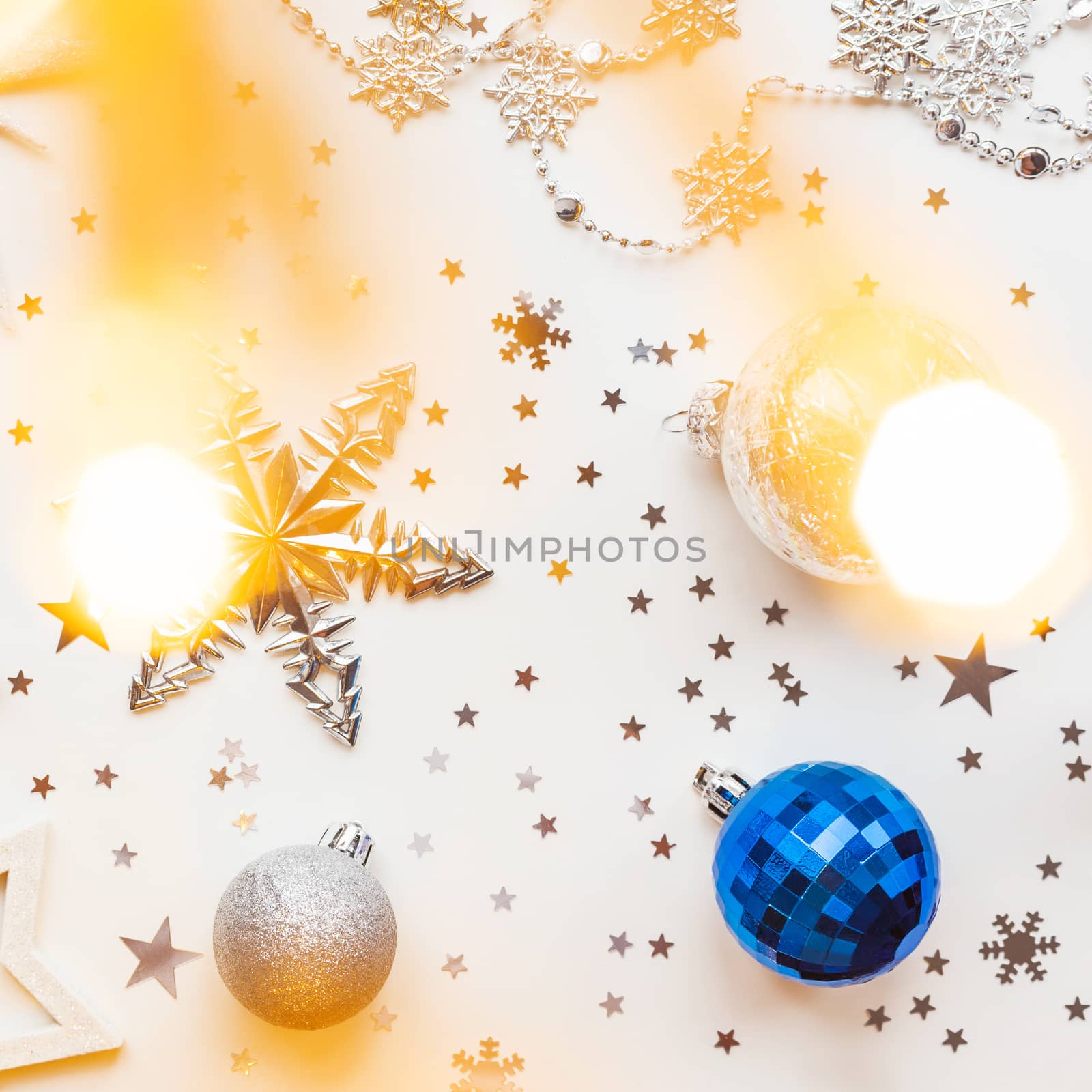 Christmas and New Year holiday background with decorations and light bulbs. Silver and blue shining balls, white snowflakes and star confetti. Flat lay, top view.