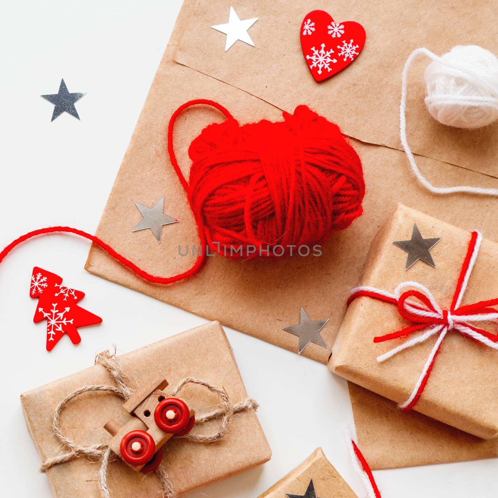 Packed Christmas and New Year DIY presents in craft paper. Gifts tied with threads. Boxes, red heart and Christmas tree symbols on white background.