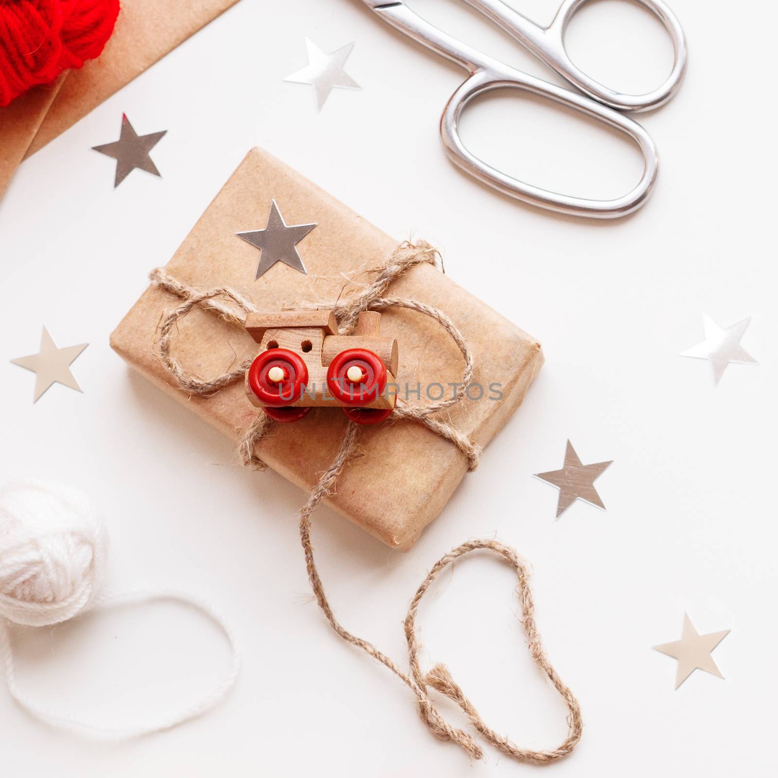 Christmas and New Year DIY presents in craft paper. Holiday gifts tied with white and red threads with toy train as decoration.