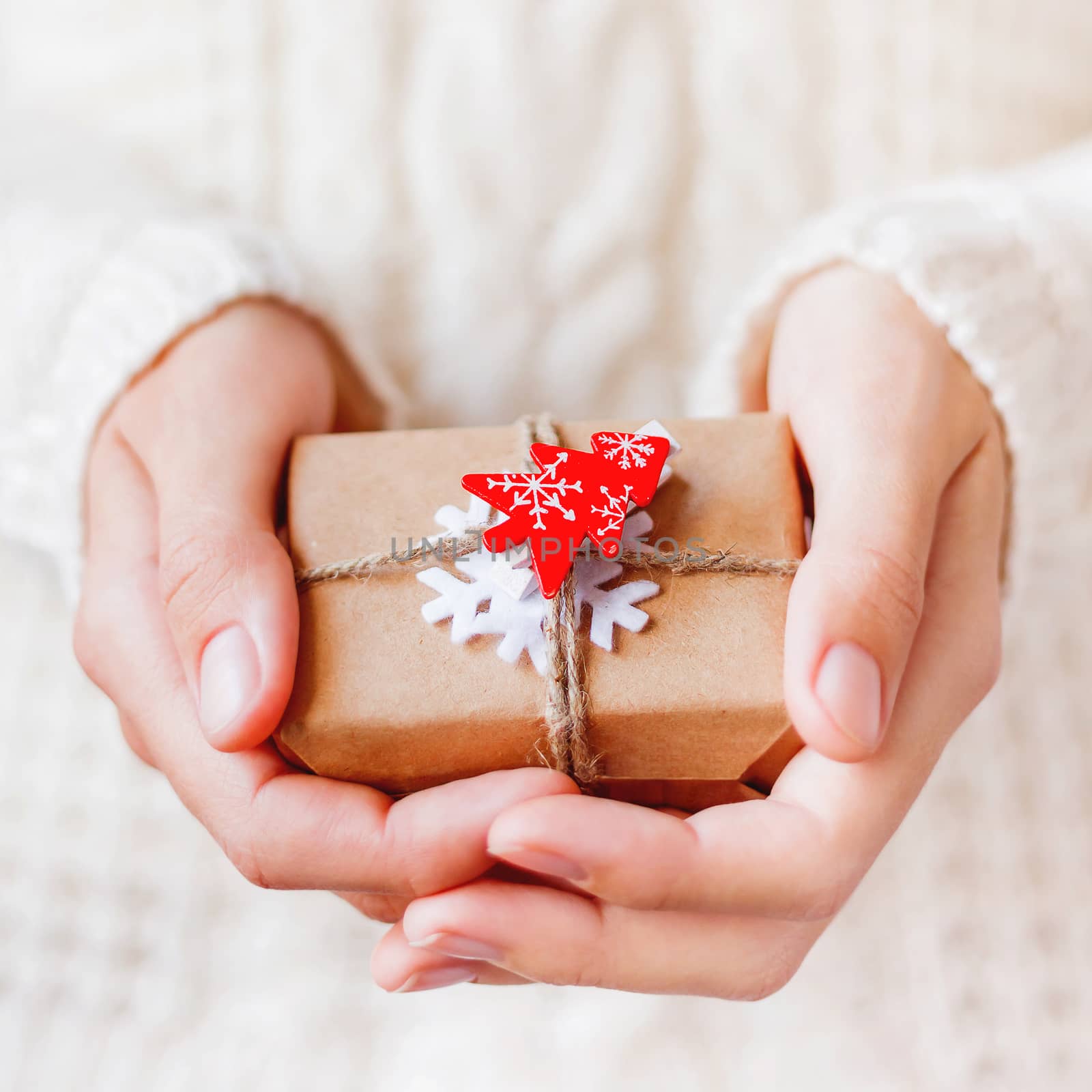 Woman in knitted sweater is holding Christmas present packed in by aksenovko