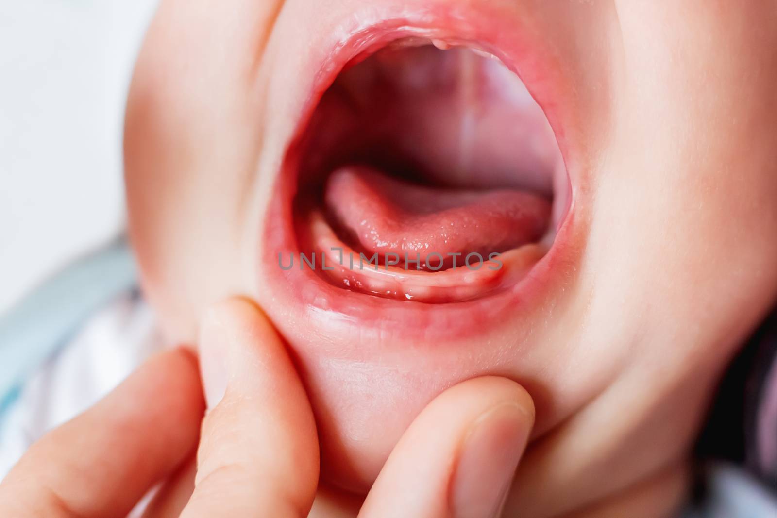 Close up photo of crying 3 months old baby mouth. Bare gums without teeth.